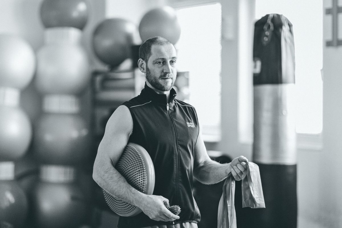 Riccardo, Physiotherapeut bei Die Gesundmacher, mit Balancekissen und Trainingsband