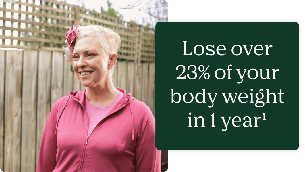 Smiling woman with short, curly pink hair wearing a pink jacket standing outdoors next to text reading 'Lose over 23% of your body weight in 1 year¹' on a dark green background.