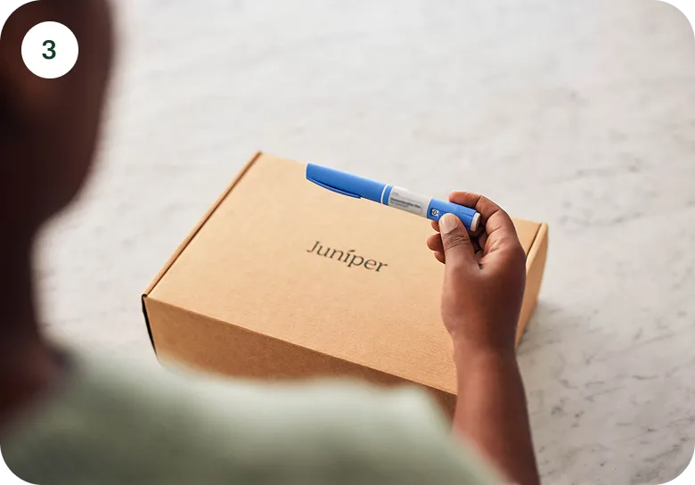 Person holding a blue medical device above a cardboard box labeled Juniper.