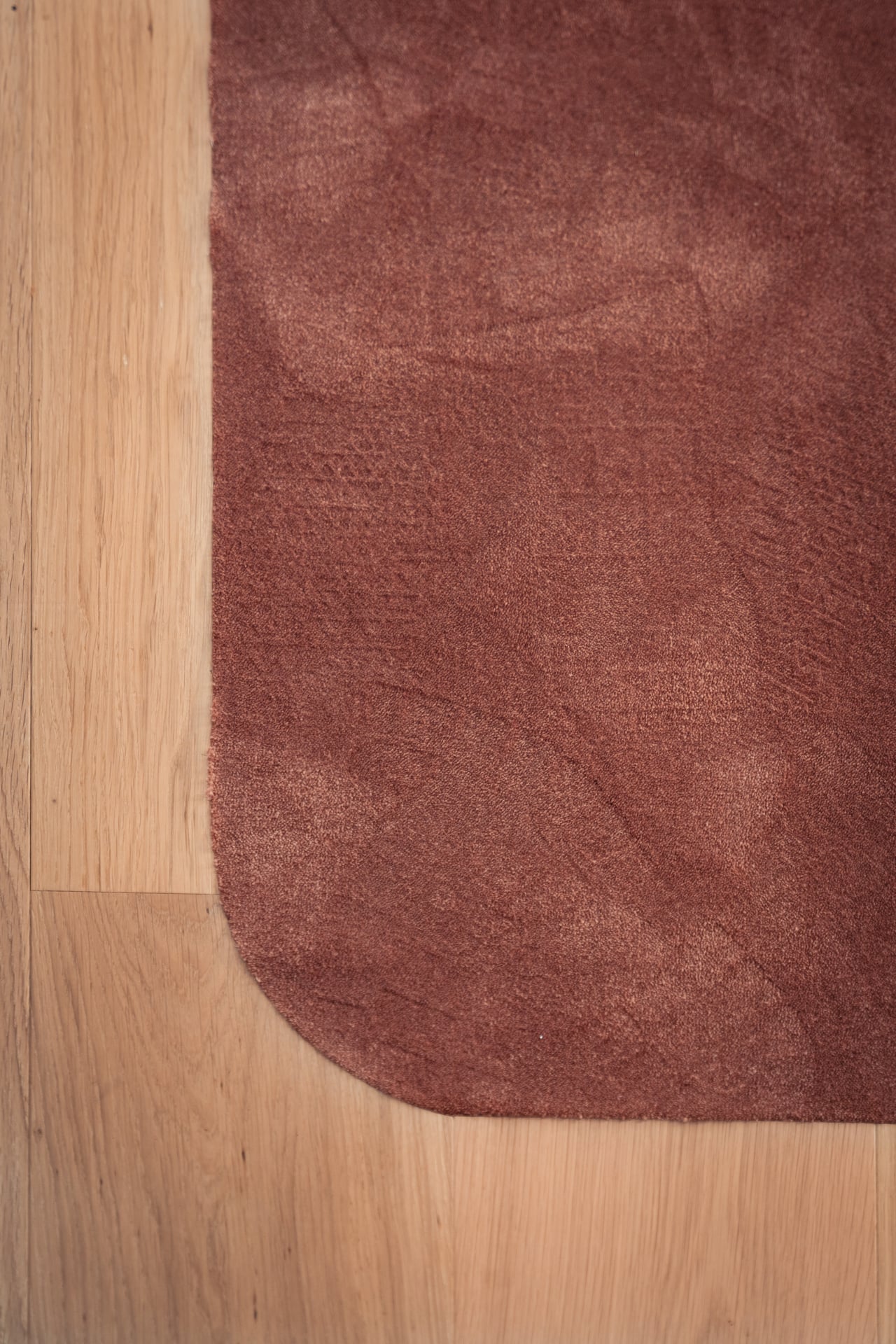 Close-up van een donkerroze tapijt op een houten vloer.