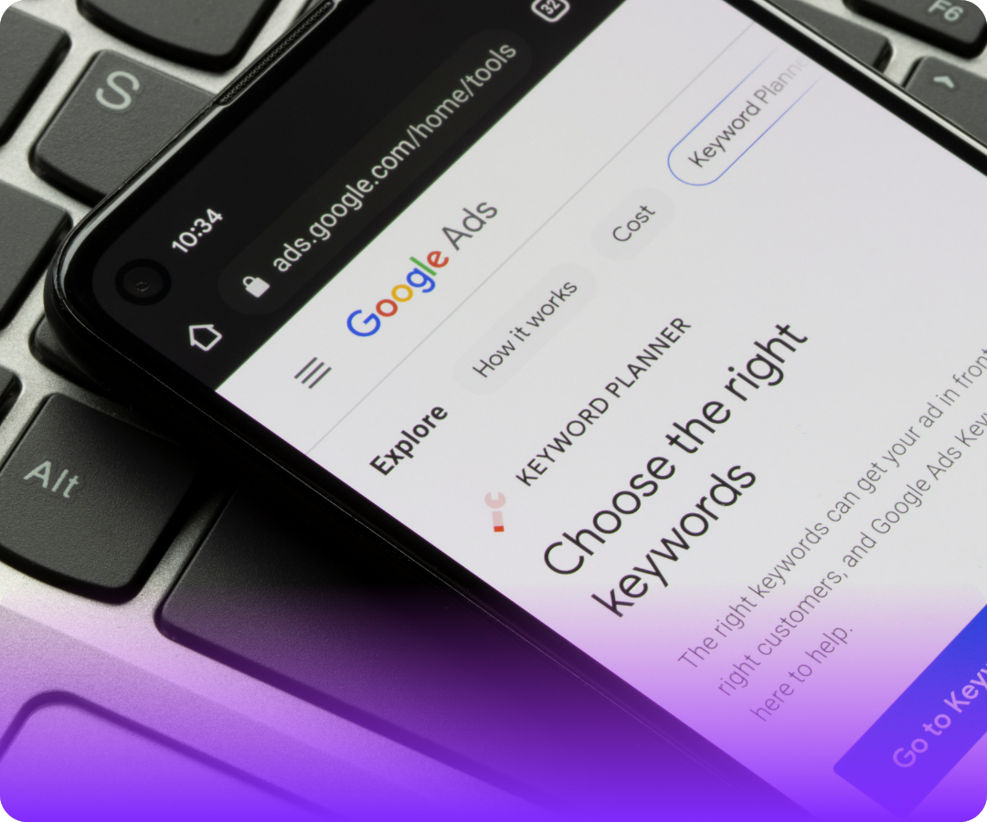 Smartphone displaying Google Ads Keyword Planner page on a black laptop keyboard.