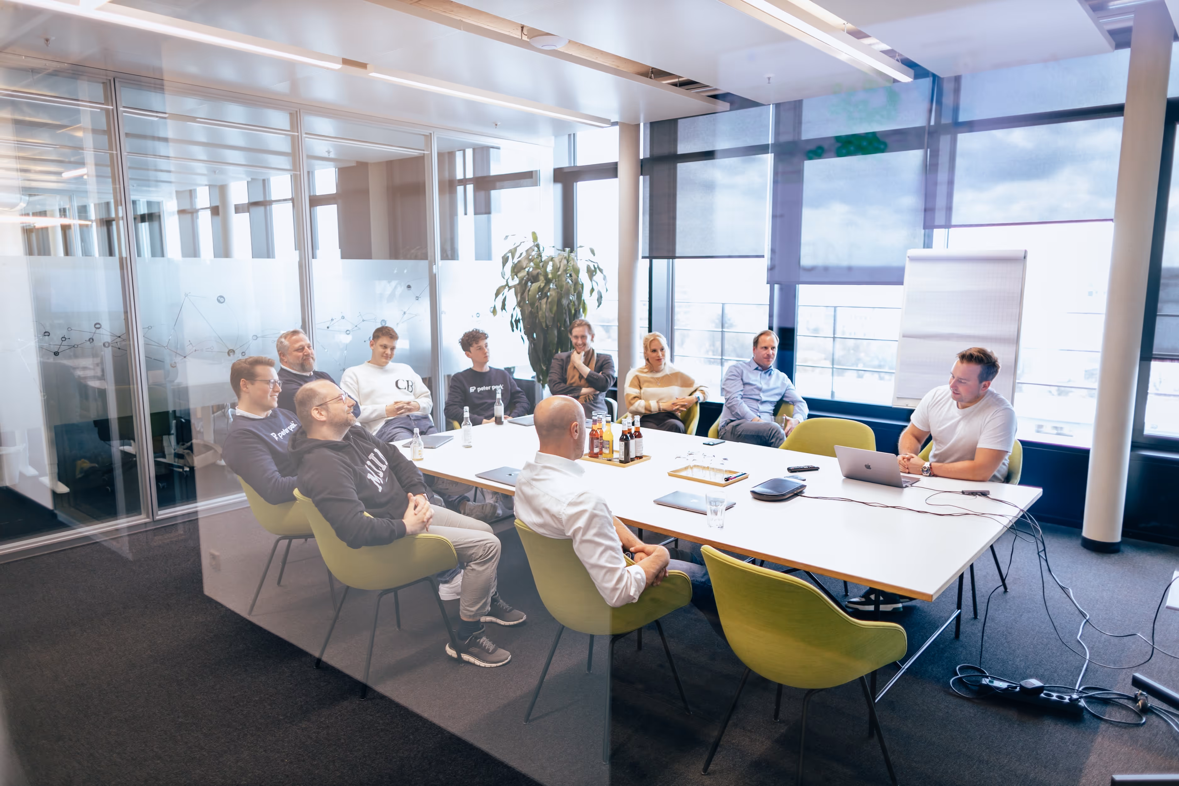 Neun Personen sitzen in einem modernen Konferenzraum um einen Tisch bei einem Meeting.