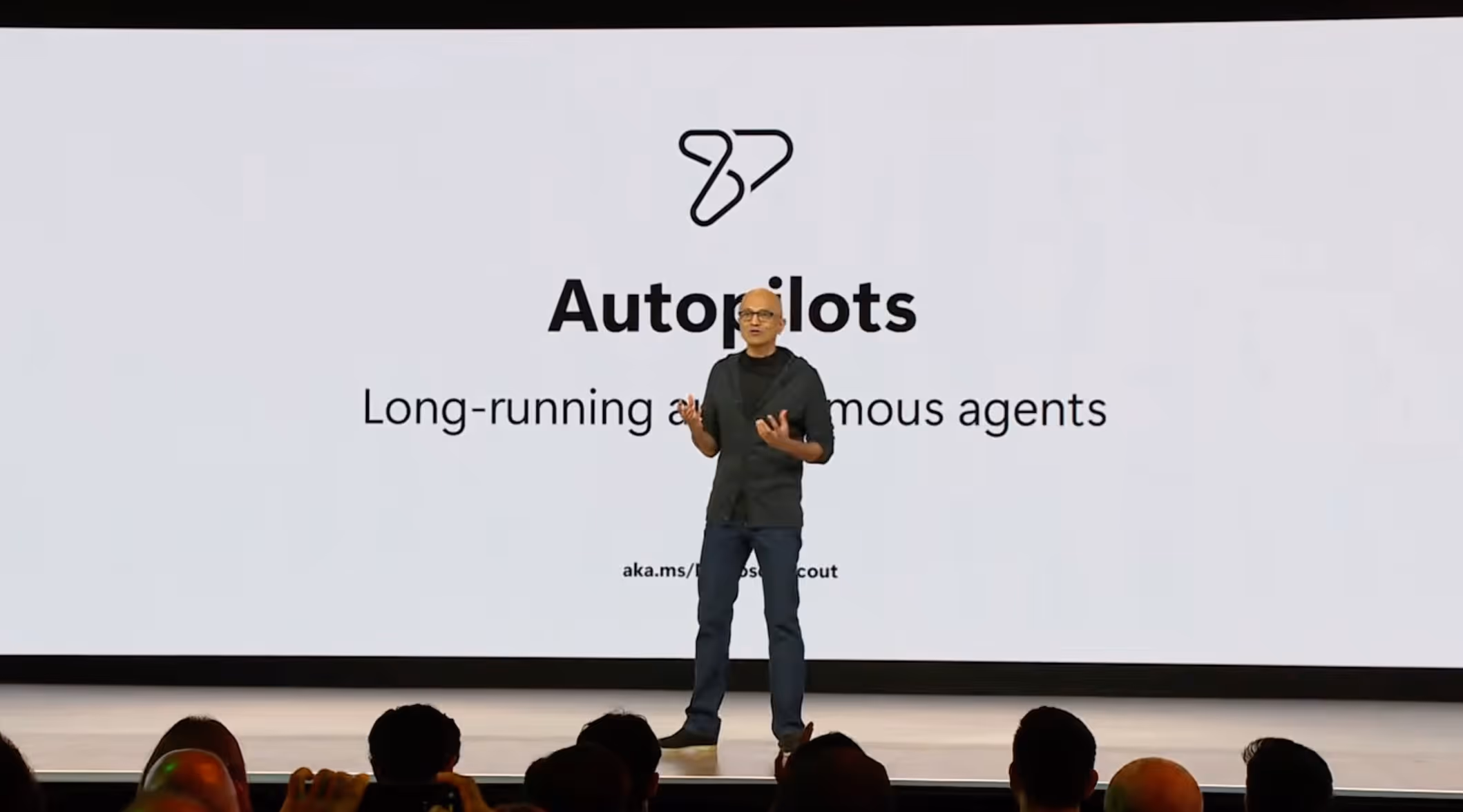 Satya Nadella stellt auf der Microsoft Build 2026 die Autopilots vor, im Hintergrund die Folie Long-running autonomous agents