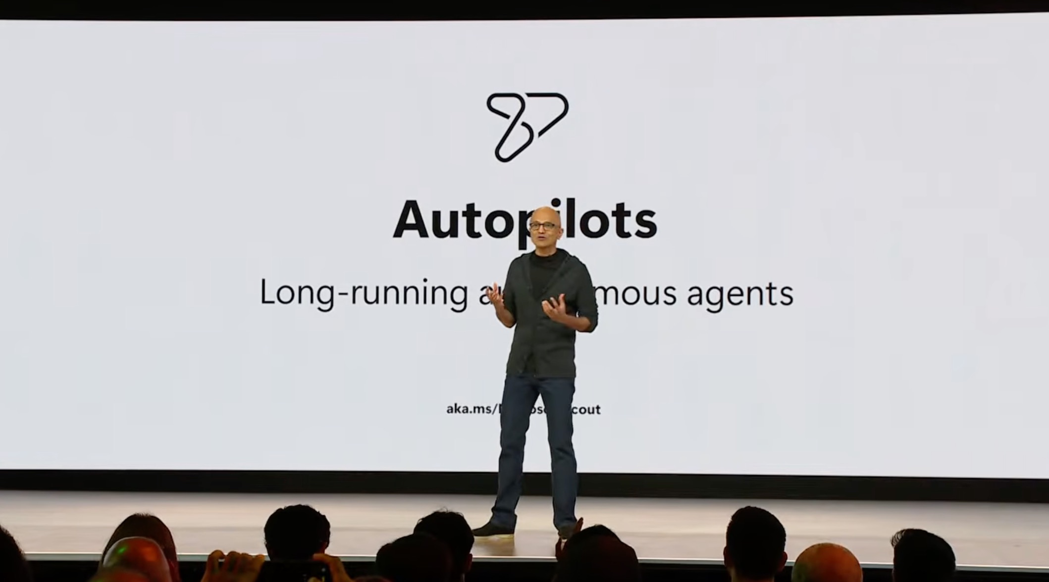 Satya Nadella stellt auf der Microsoft Build 2026 die Autopilots vor, im Hintergrund die Folie Long-running autonomous agents