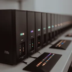 Close-up of a row of black network servers with glowing indicator lights in a data center.