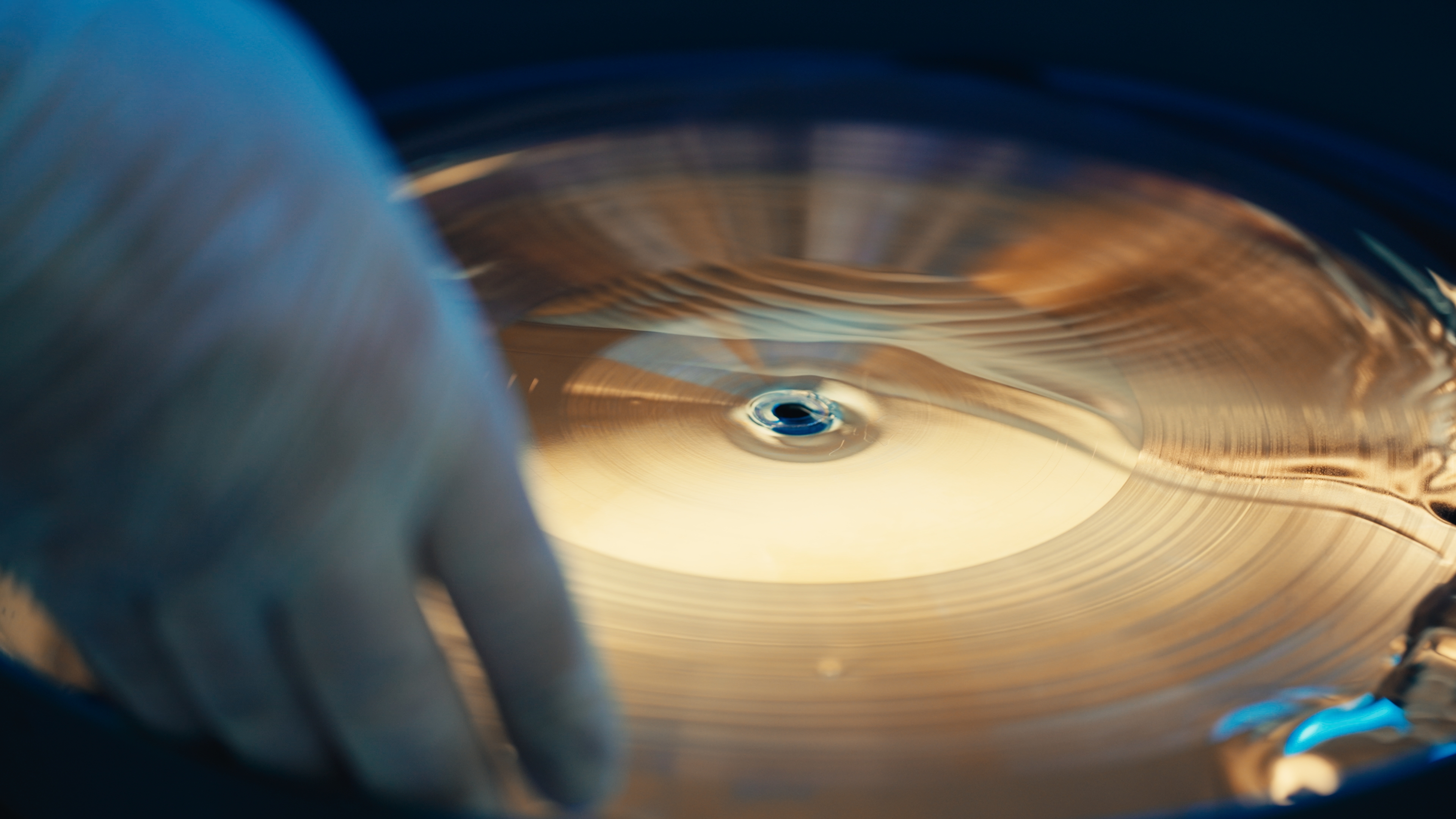 Close-up of a hand adjusting a spinning record on a turntable.