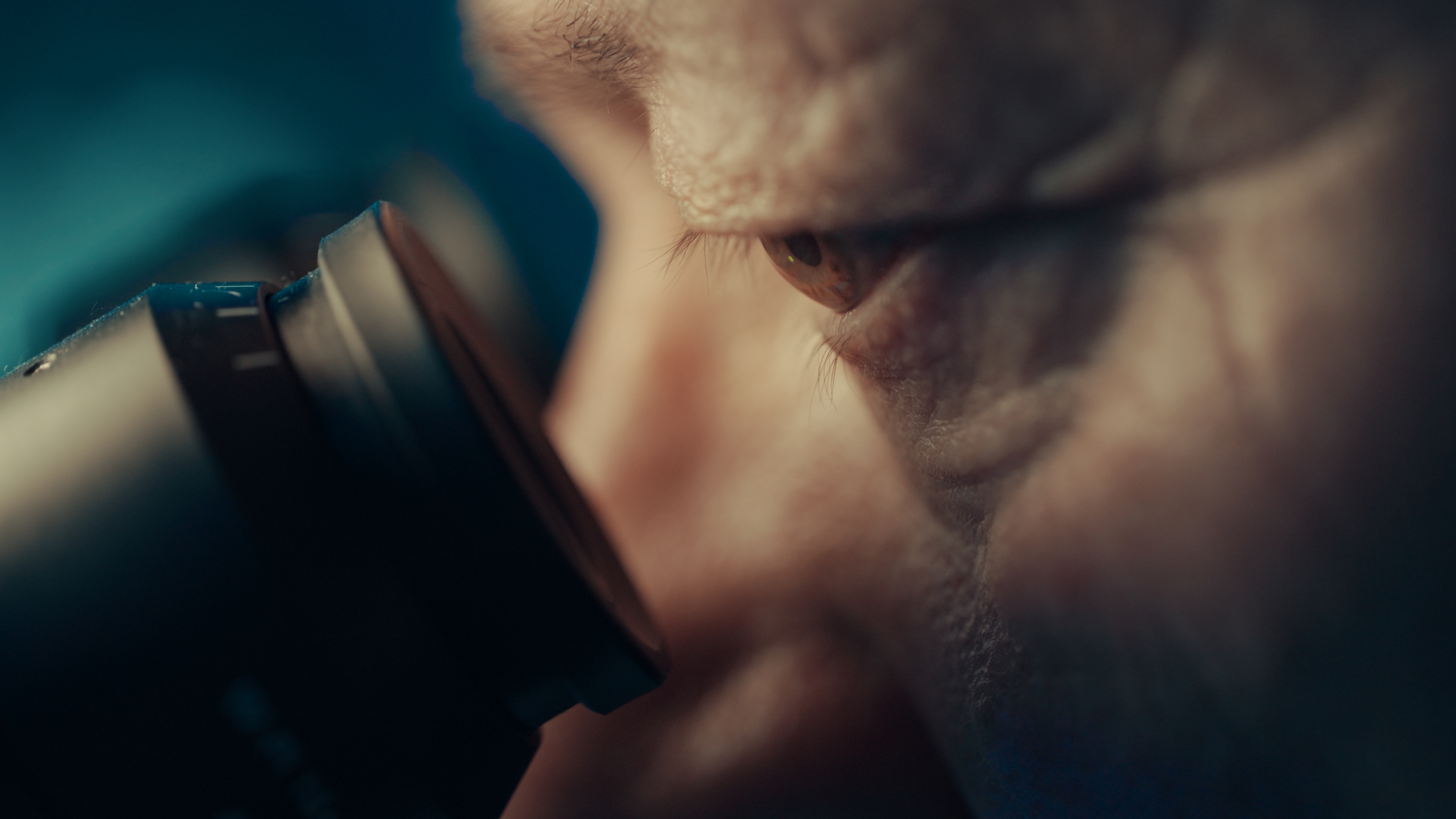 Close-up of a human eye looking through the eyepiece of a microscope.