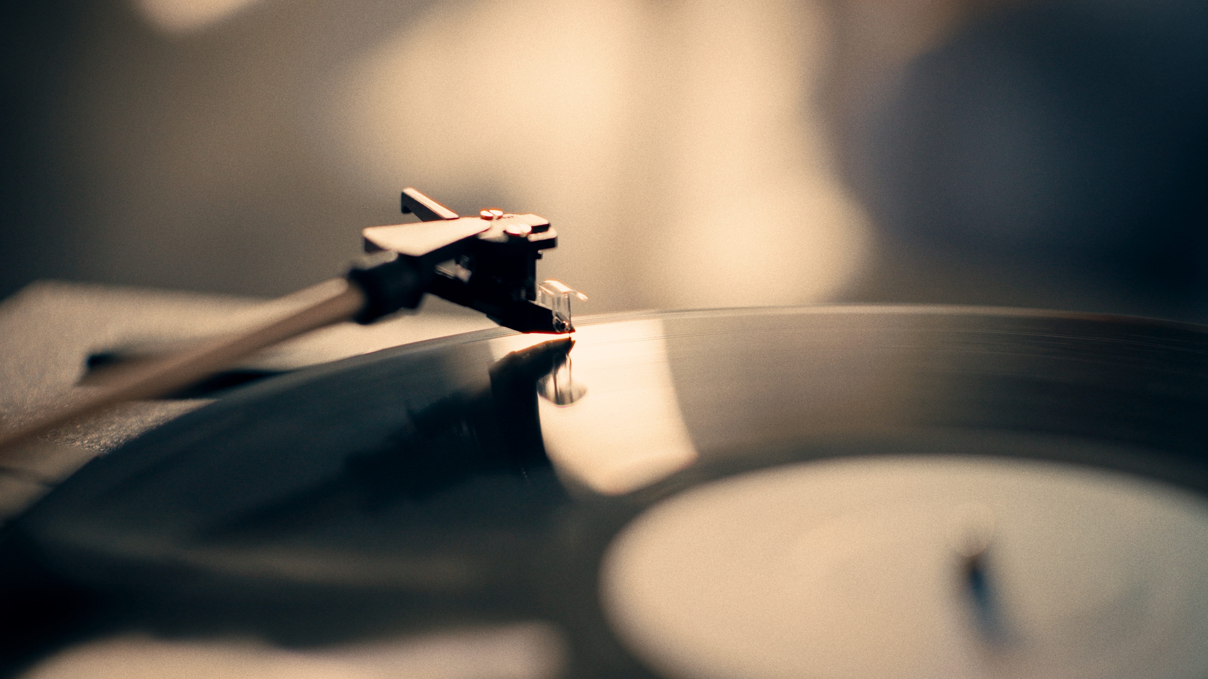 Close-up of a record player pin touching a record, with a blurred background.