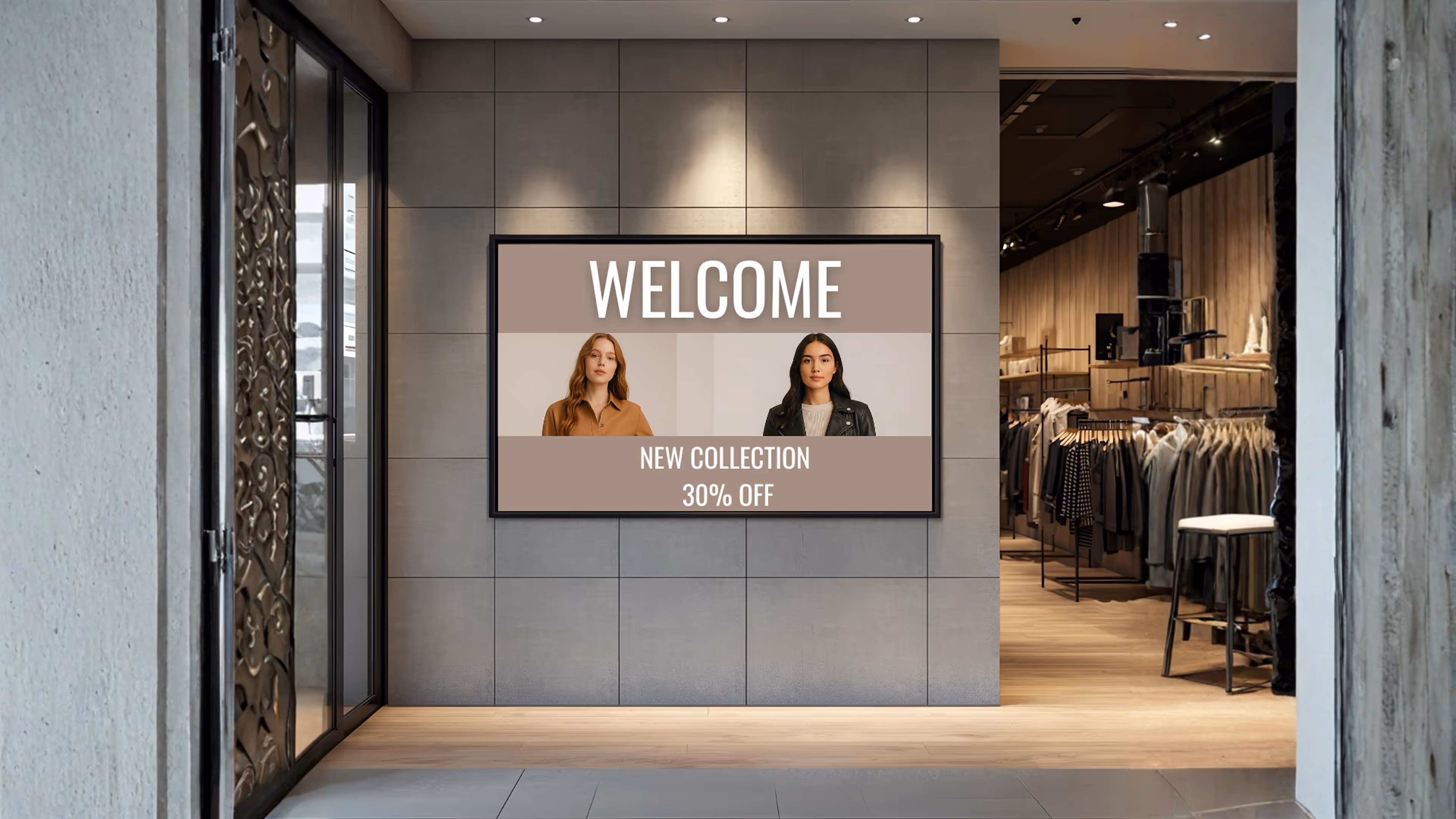 Eingangsbereich eines Bekleidungsgeschäfts mit digitaler Anzeige „Welcome“, die zwei Frauen und die Botschaft „New Collection 30% Off“ zeigt.