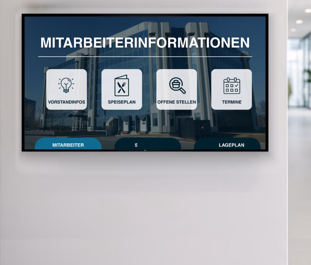 Bildschirm an der Wand zeigt Mitarbeiterinformationen mit Symbolen für Vorstandinfos, Speiseplan, offene Stellen und Termine vor einem Bürogebäude.