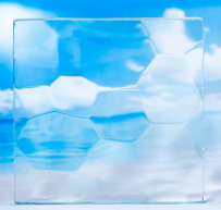 Transparent hexagonal glass tiles with a blue sky and white clouds visible behind them.