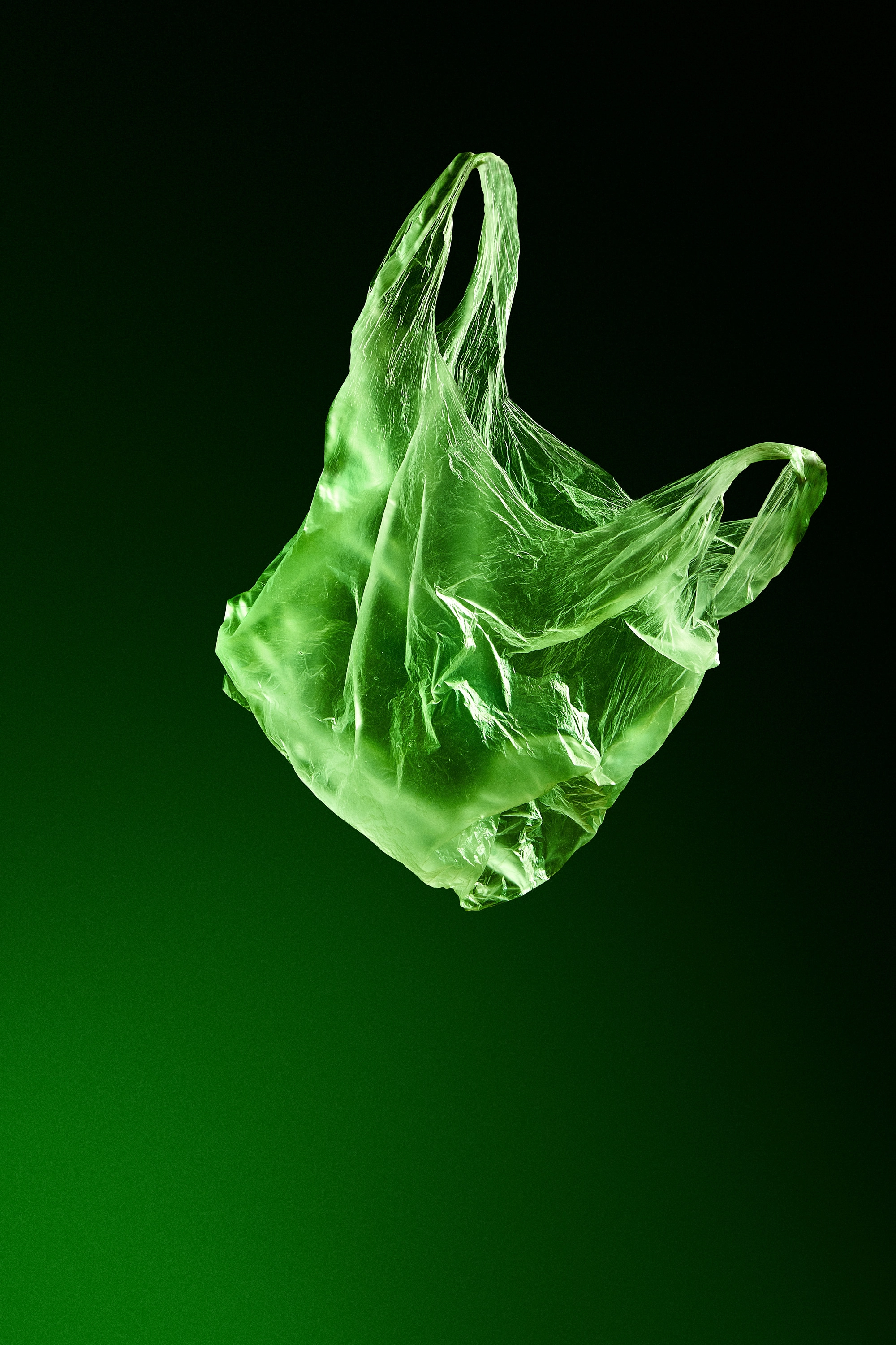 Translucent plastic bag floating against a dark green gradient background.