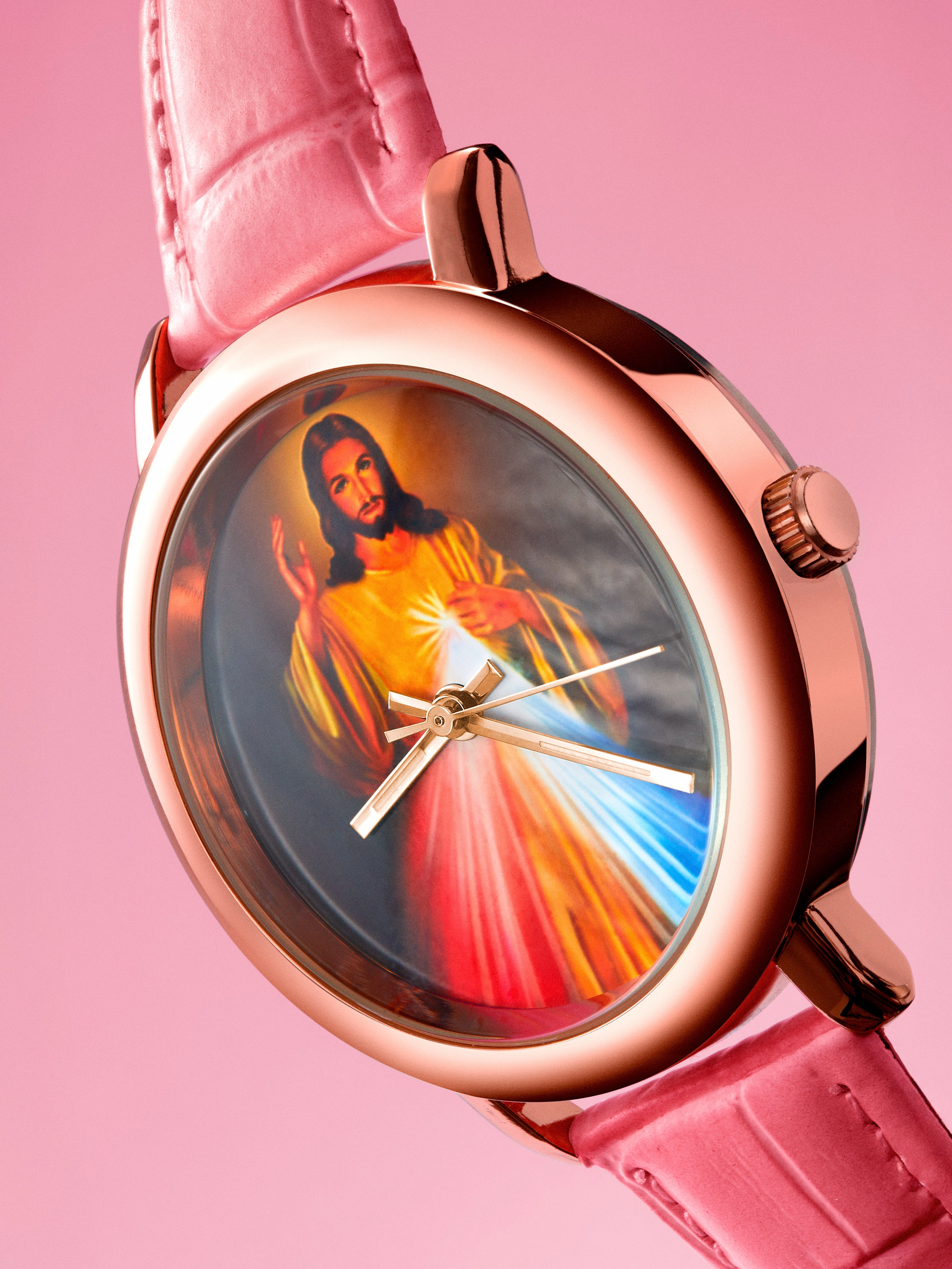 Close-up of a wristwatch with a rose gold case and pink leather strap, featuring an image of Jesus with radiant light on its dial.