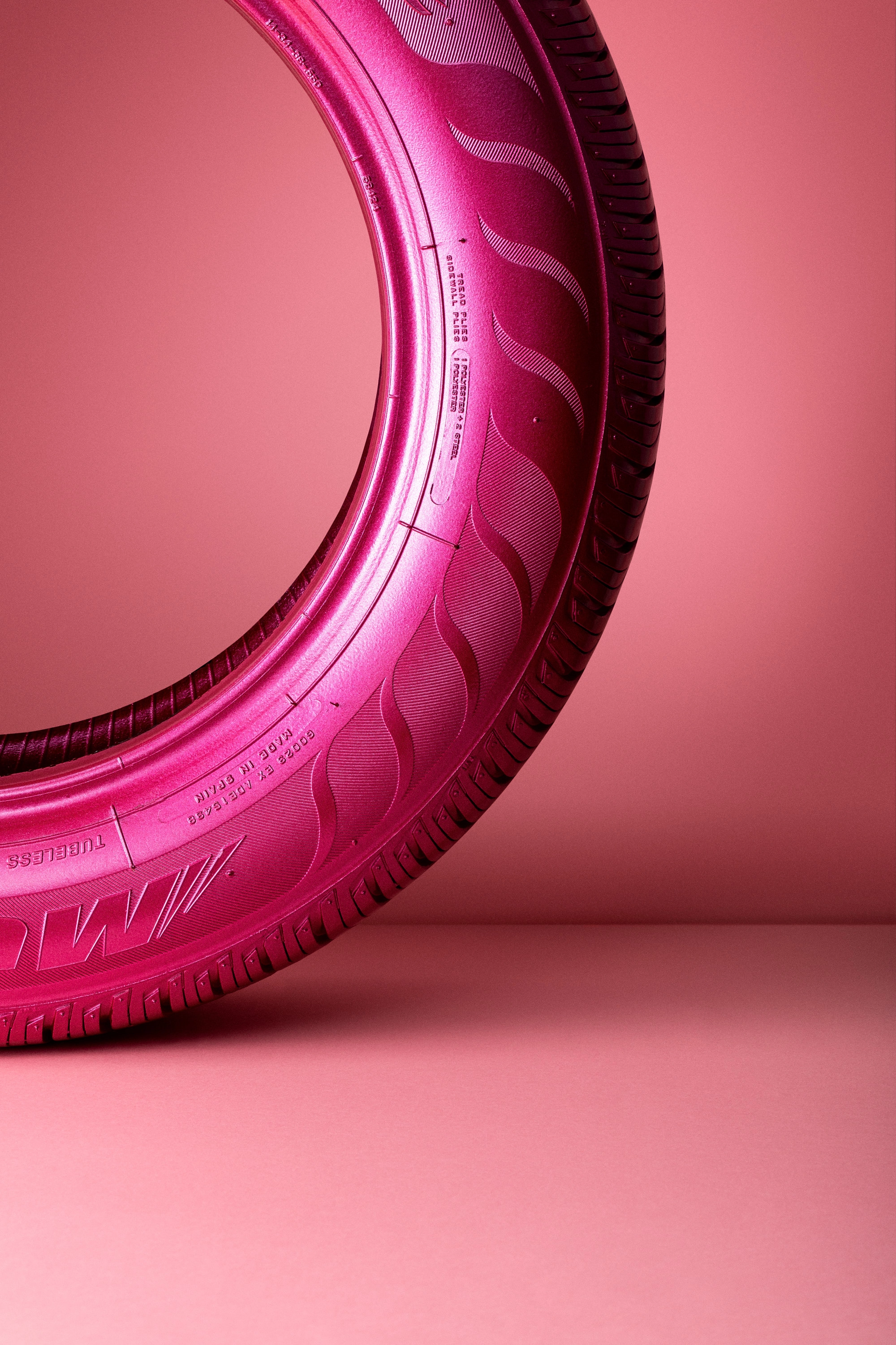 Close-up of a pink tire standing vertically against a pink background.