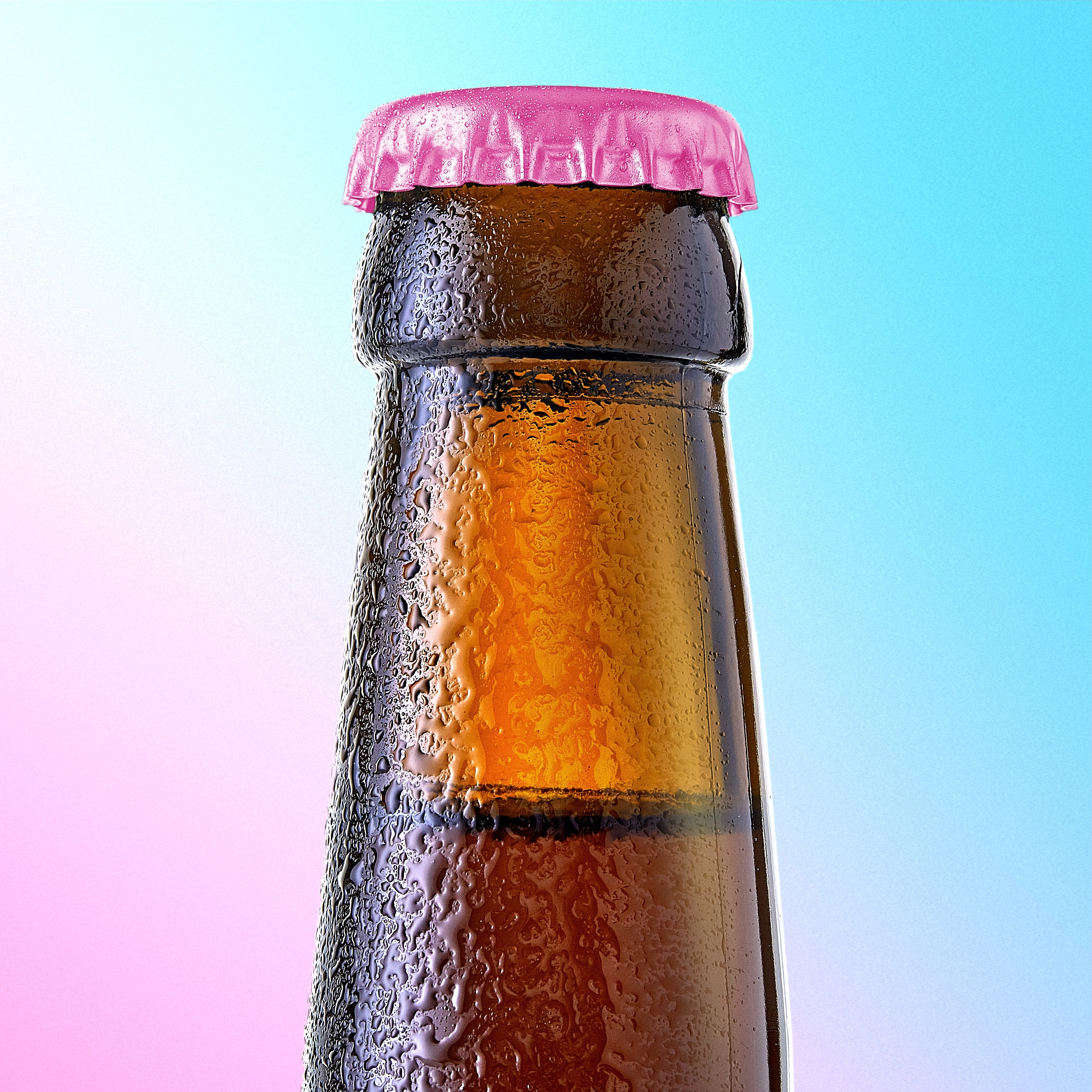Close-up of a brown glass bottle neck with condensation and a pink bottle cap against a blue and pink gradient background.