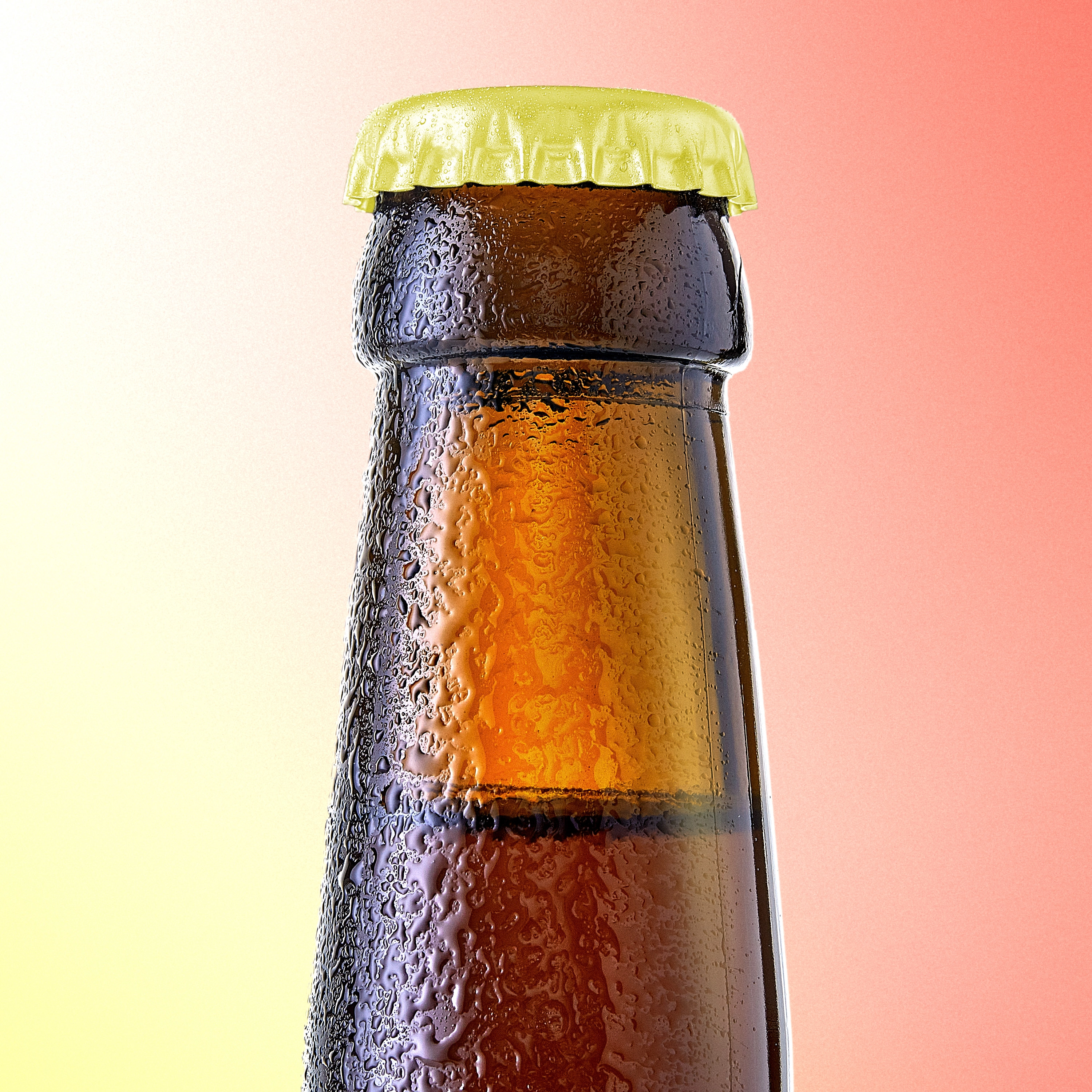 Top portion of a brown glass bottle with a yellow cap covered in condensation droplets.