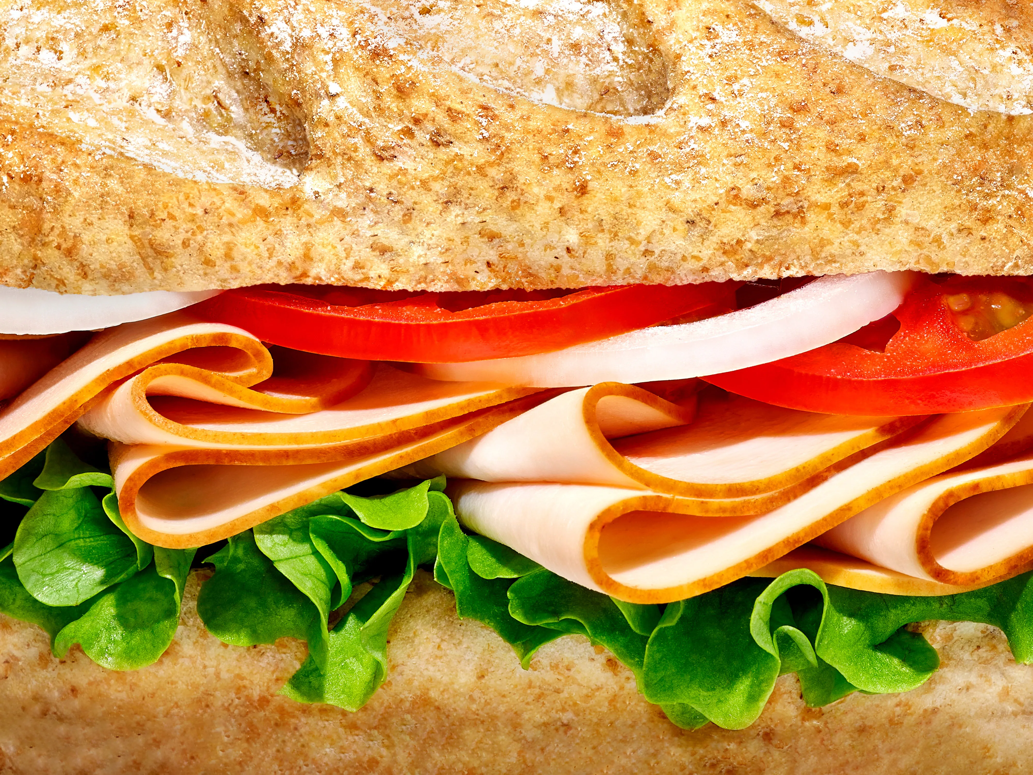 A can of beer labeled 'Tiles' lying on a dark green velvet sofa with an orange patterned cloth, photos, and a bowl of pasta in the background.