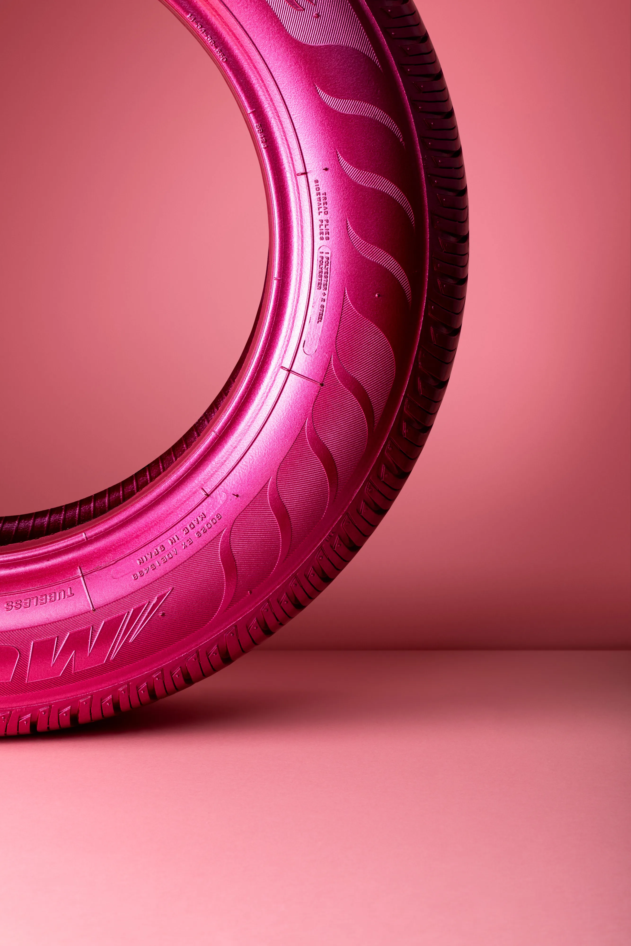 Close-up of a pink car tire standing upright against a matching pink background.