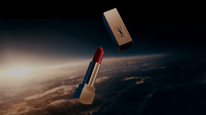 Broken white plate with spaghetti pasta and clams on a blue patterned tablecloth, with a green-stemmed glass and utensils nearby.