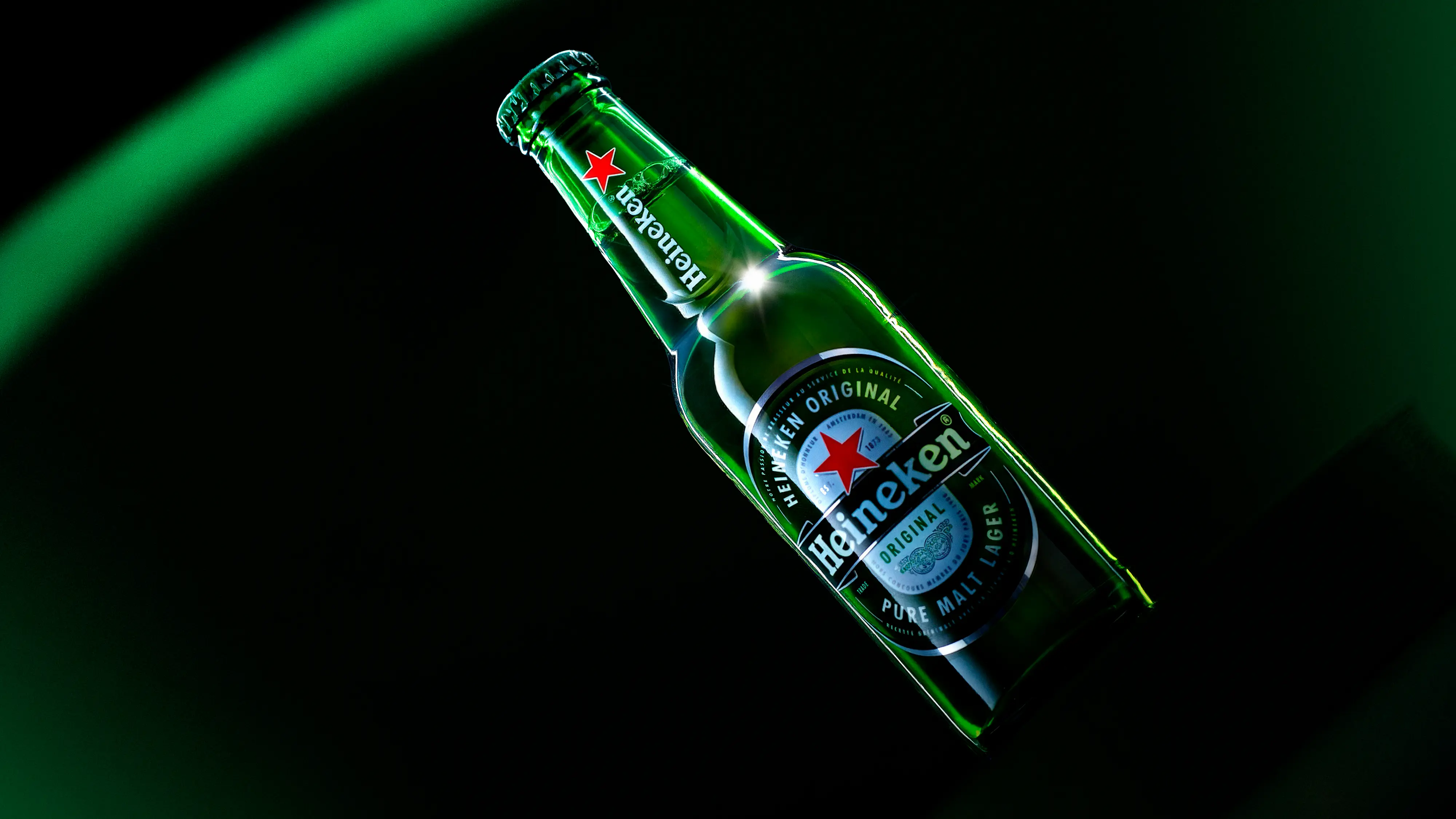 Brown leather shoe with yellow laces on wooden floor next to a yellow fringed blanket, dice in a wooden box, a can labeled Double Trouble, and a bottle labeled Mick Lager.