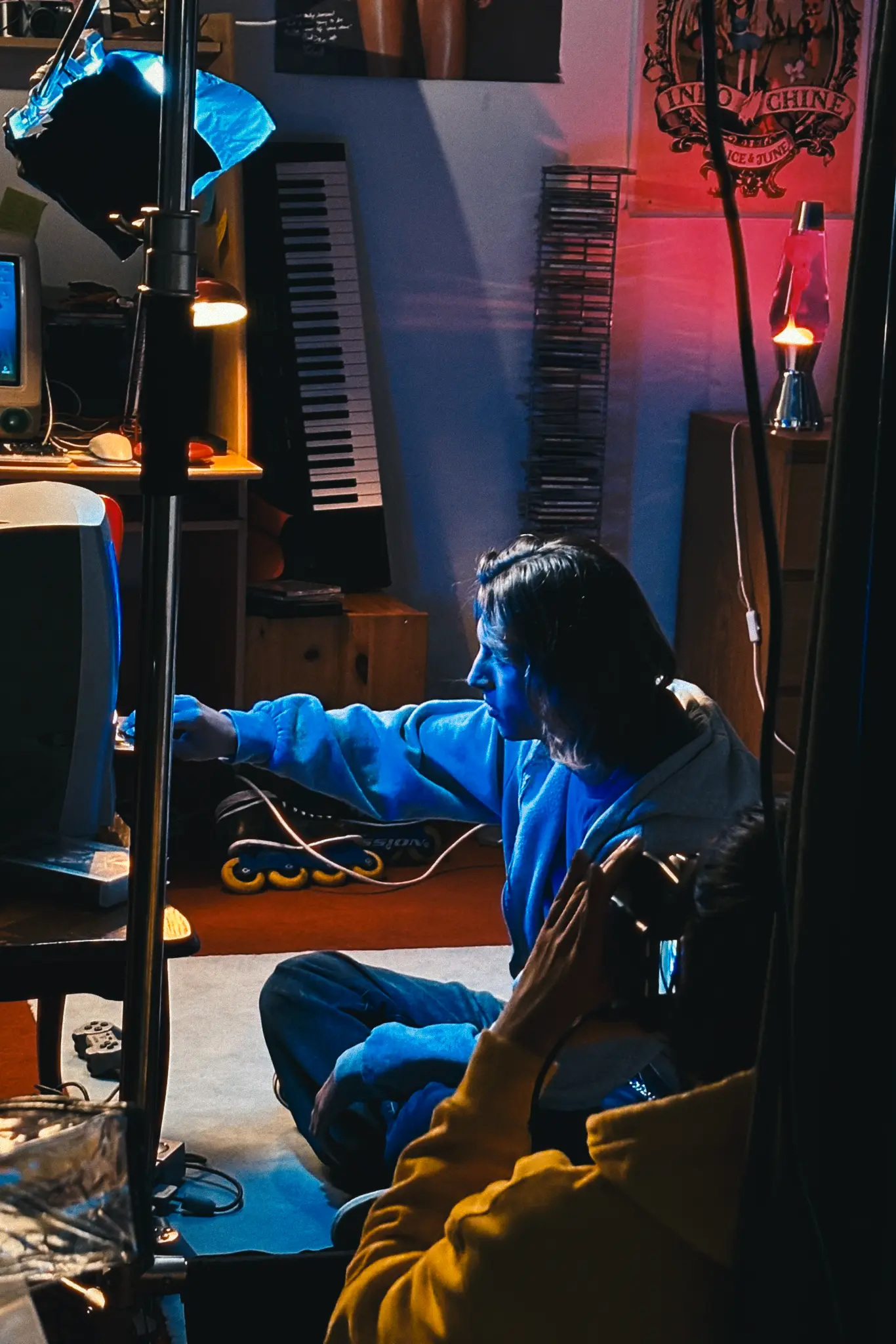 Camera monitor displaying a video frame focused on two people’s legs under red lighting with various camera settings visible.