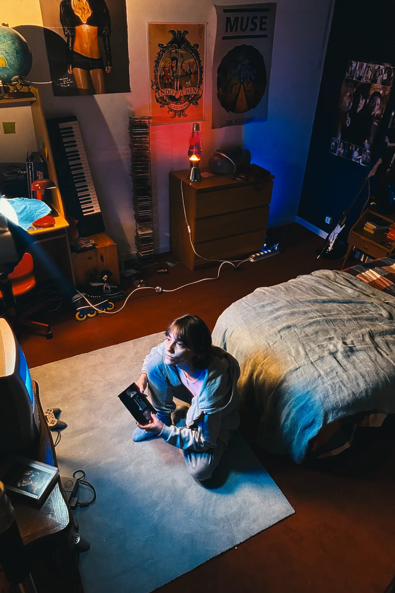 Camera monitor displaying a video frame focused on two people’s legs under red lighting with various camera settings visible.