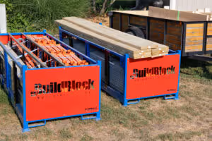 Two metal crates on grass, one filled with wooden planks and the other with orange construction blocks, both labeled BuildBlock.
