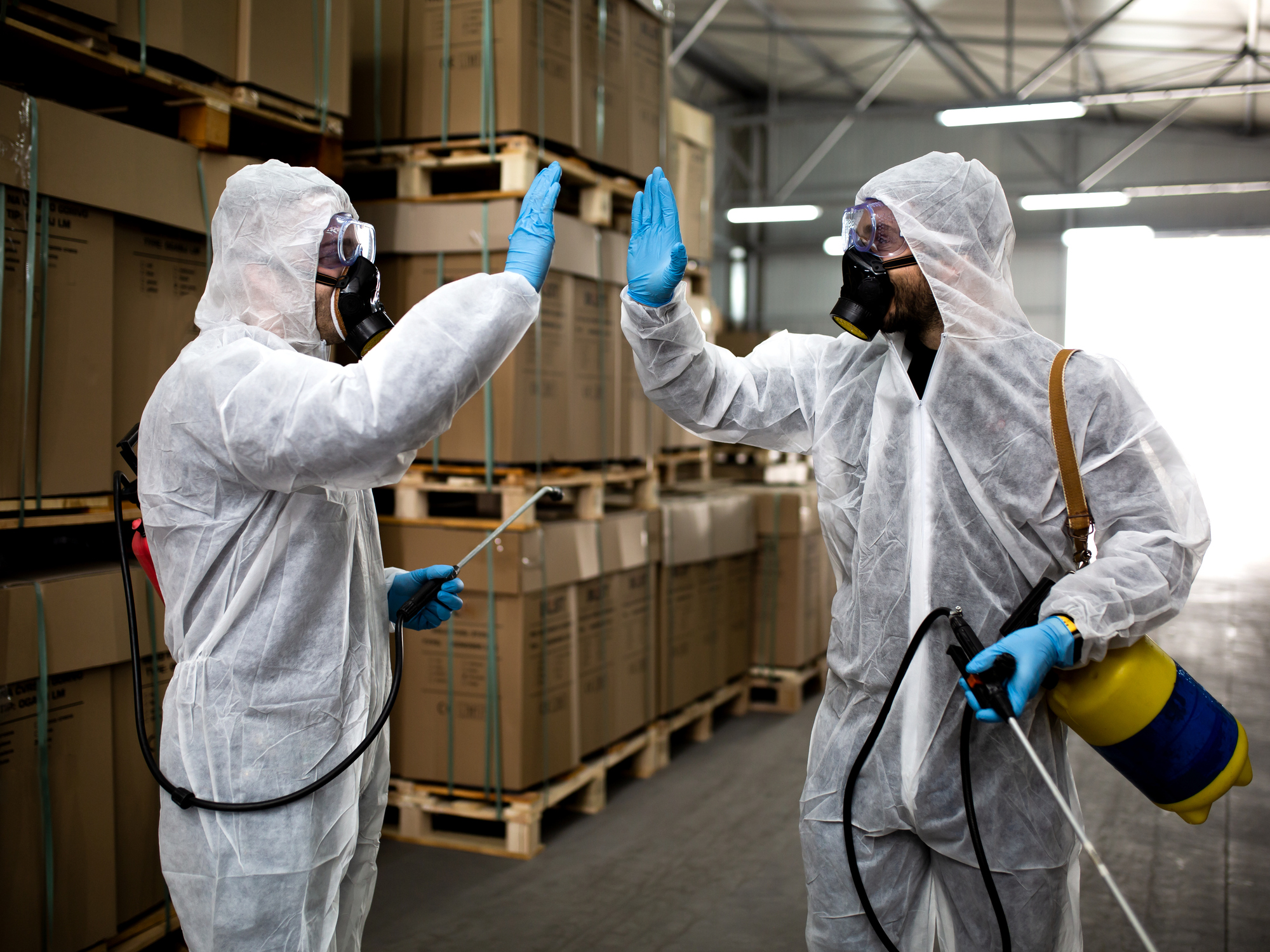 Workers in protective suits high-five after disinfection job