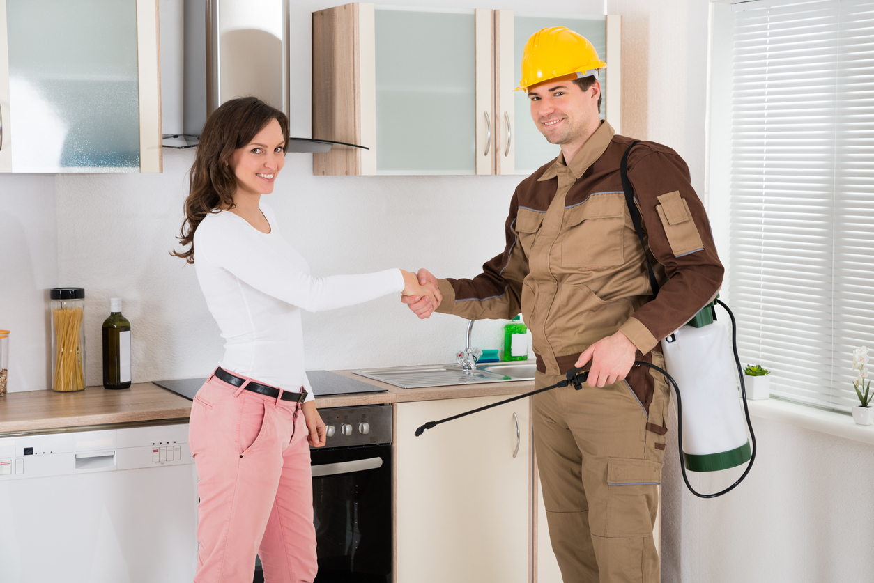 Pest control technician shaking hands with homeowner in kitchen