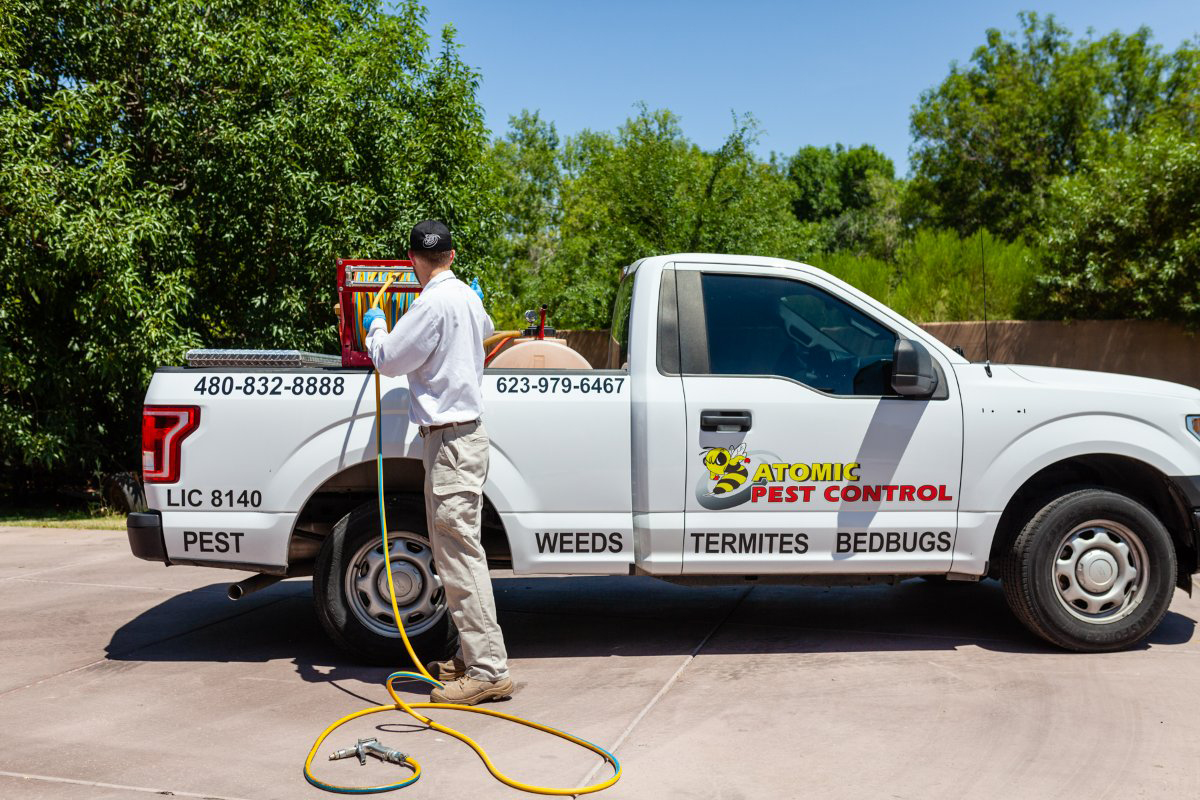 Pest control technician standing next to white truck with equipment