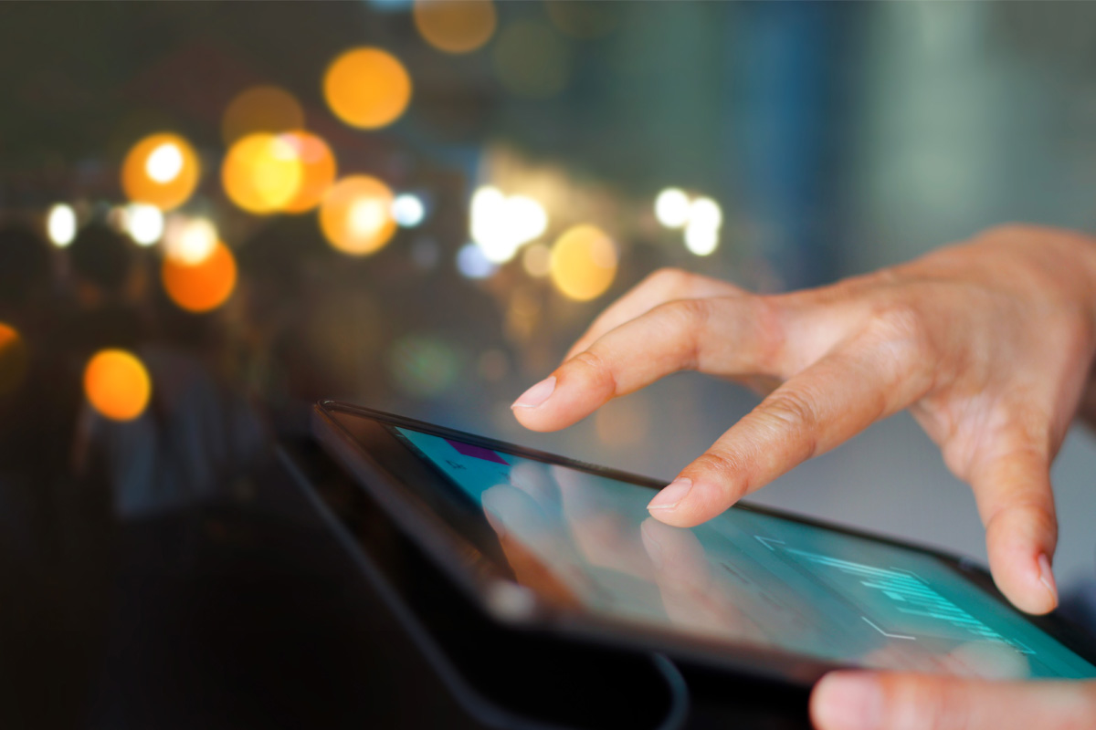 Hand touching smartphone screen with blurred lights in background