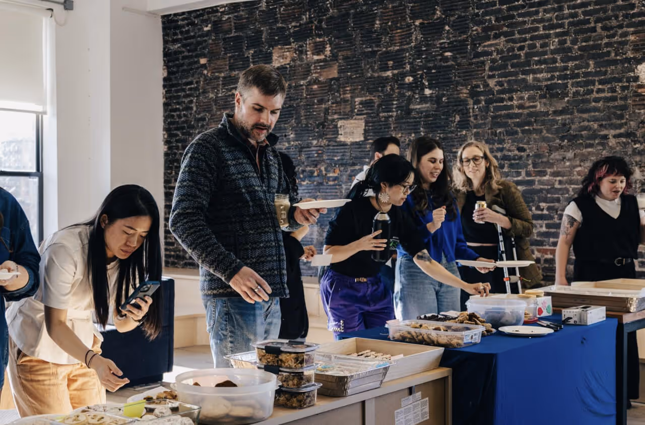 Coworkers gather around a table of food in an office break area
