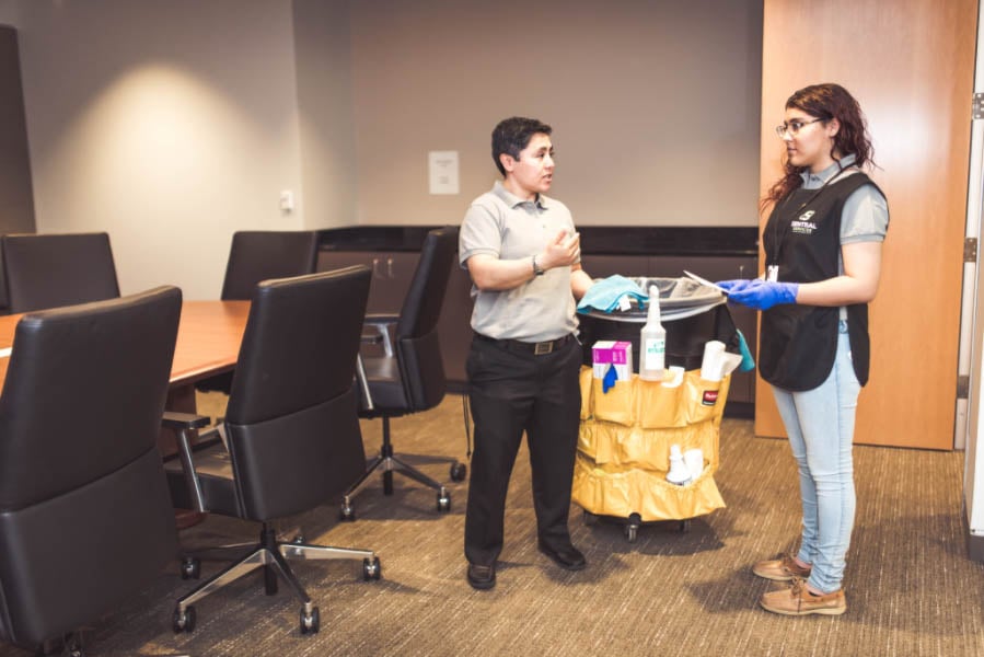 Tall white house exterior with large windows reflecting leafless trees and a stone chimney on the side.