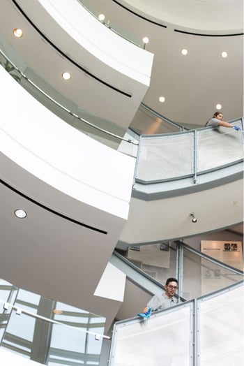 Modern office interior with metal railing stairway and blurred man in blue shirt walking.