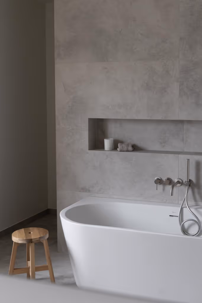 Luxe badkamerrenovatie met back-to-wall bad, inbouwnis, en tegels uit natuursteen.