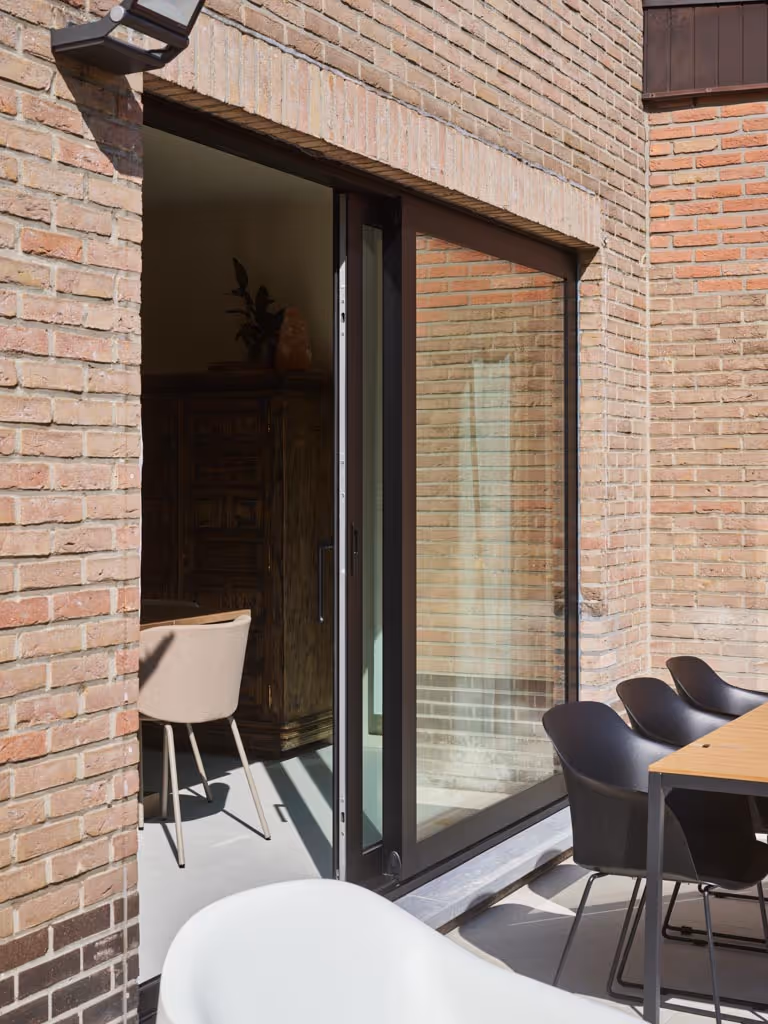 Achtergevel van gerenoveerde woning met het nieuwe donker buitenschrijnwerk als onderwerp.