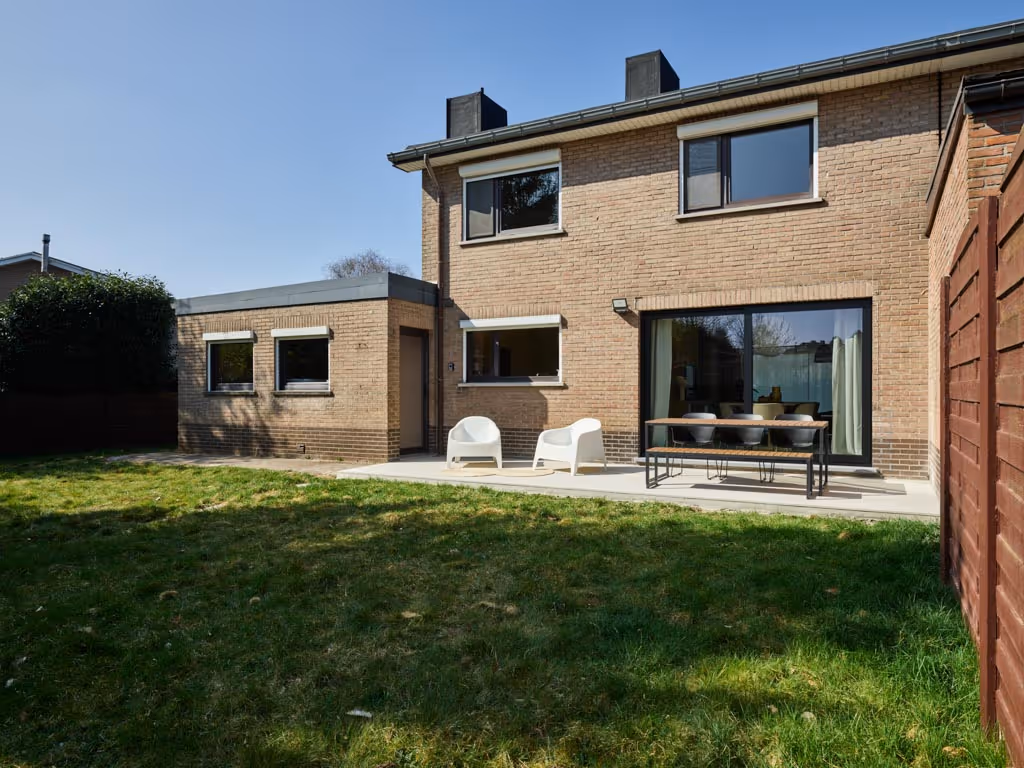 Achtergevel van gerenoveerde woning met terras en tuin na totaalrenovatie