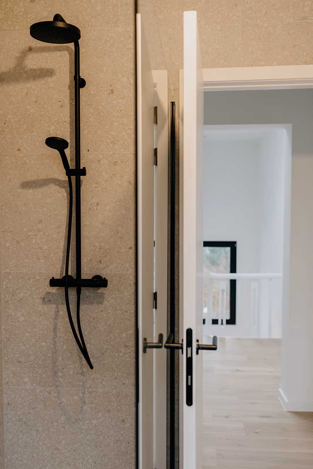 Nieuwe douche na totaalrenovatie met zwart kraanwerk, glazen douchewand en deuropening naar de nachthal.