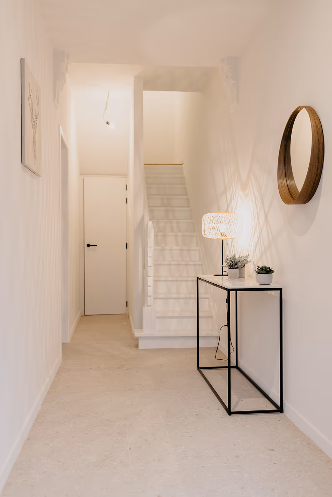 Traphal na een totaalrenovatie met wit geschilderde muren, trap en plafond.