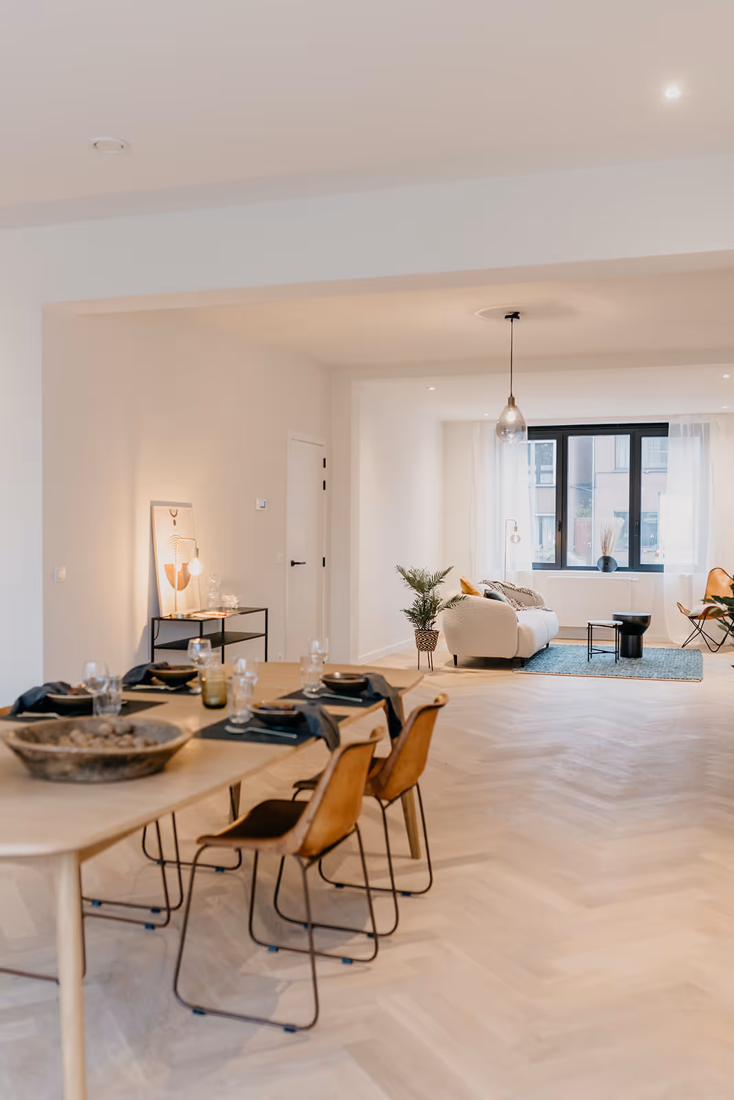 Woonruimte na een totaalrenovatie met de gedekte tafel op de voorgrond en zitruimte op de achtergrond.