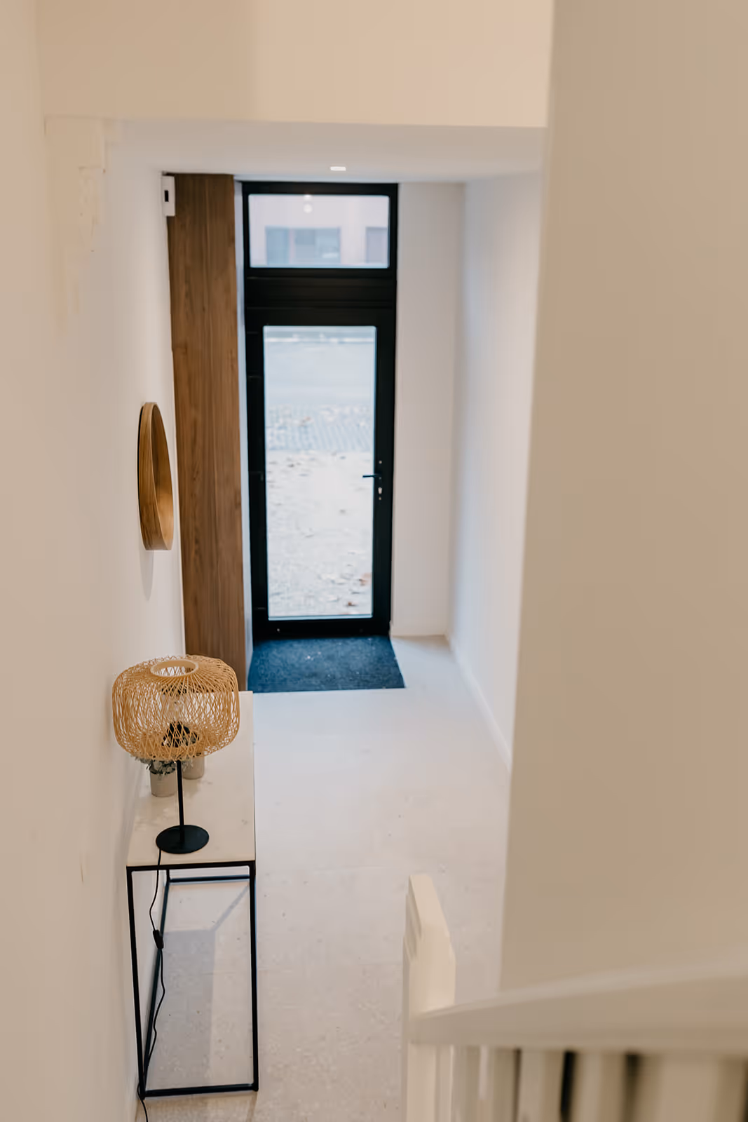 Nieuwe trap na totaalrenovatie met inkomhal en zwarte aluminium buitendeur.