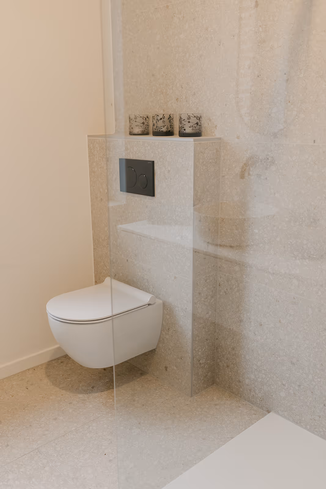 Nieuw toilet na badkamerrenovatie met zachte wandtegels, sanitaire blok en wit toilet;