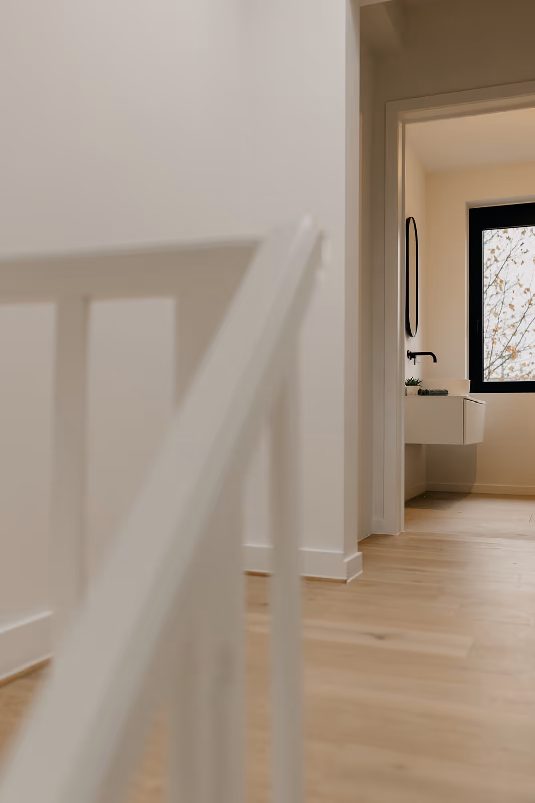 Nachthal na totaalrenovatie met trapleuning op de voorgrond en wastafel op de achtergrond.