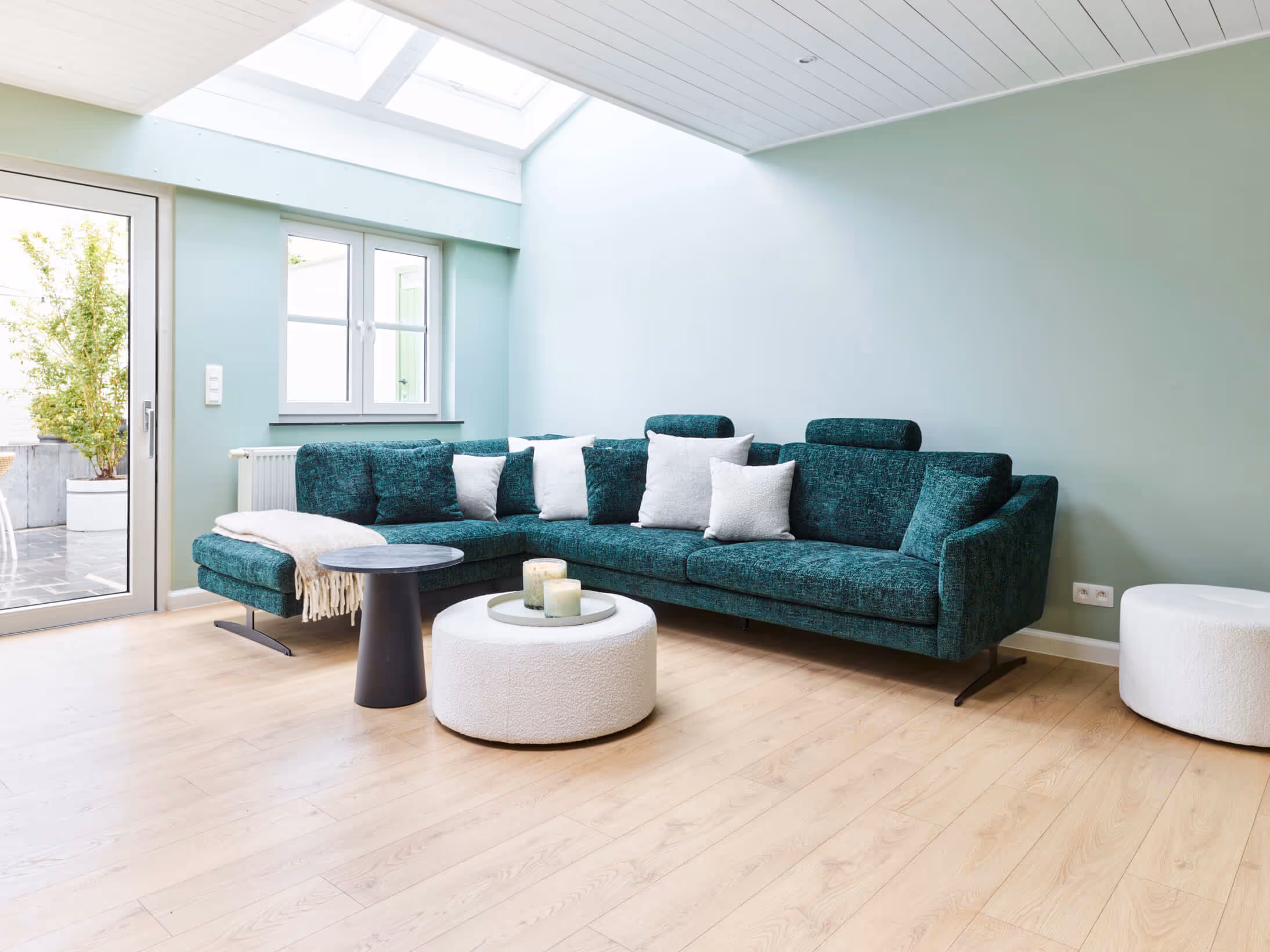 Foto van de leefruimte na totaalrenovatie met lichte tinten in combinatie met een donkere zetel.