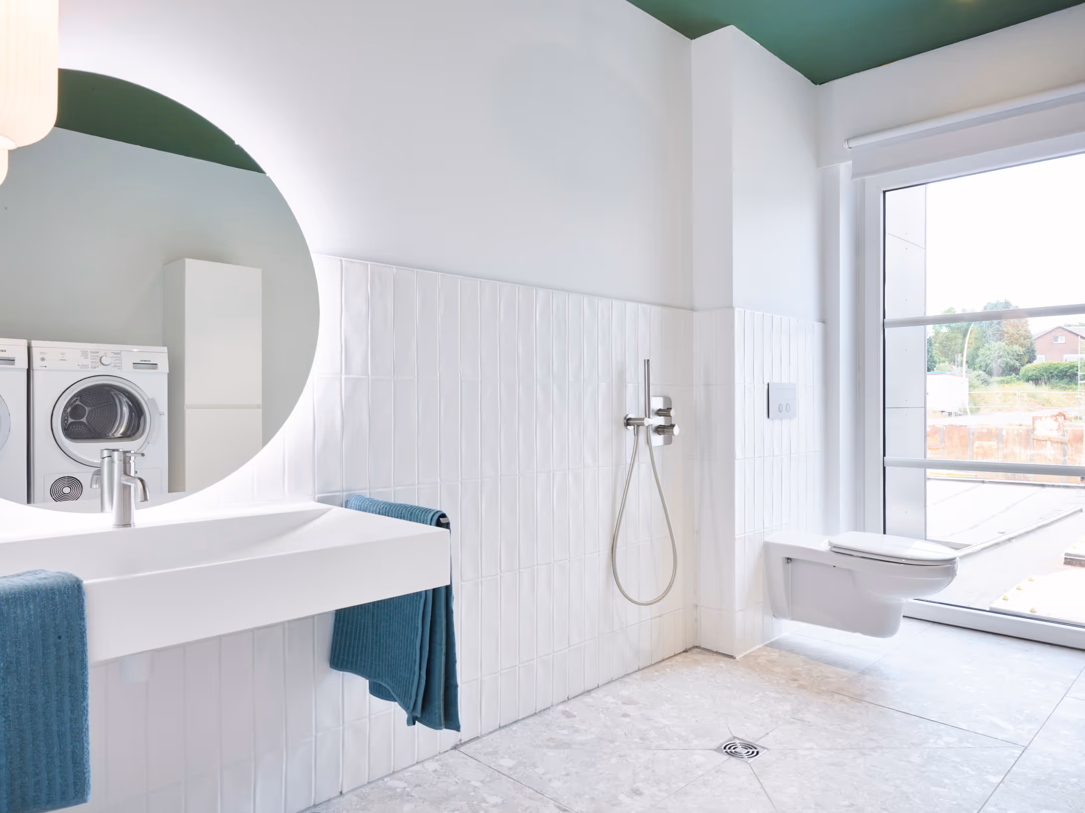 Rolstoeltoegankelijke badkamer na totaalrenovatie met verhoogde wastafel, open douche en rolstoeltoegankelijk toilet.