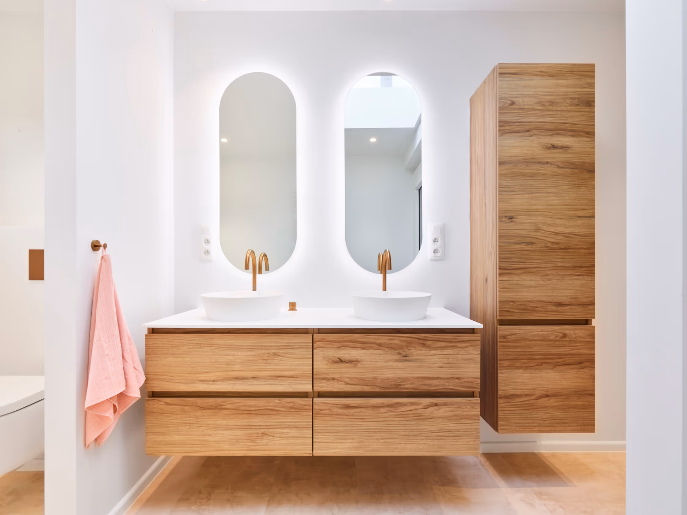 Badkamer na totaalrenovatie met frisse kleuren en warme houten meubels.