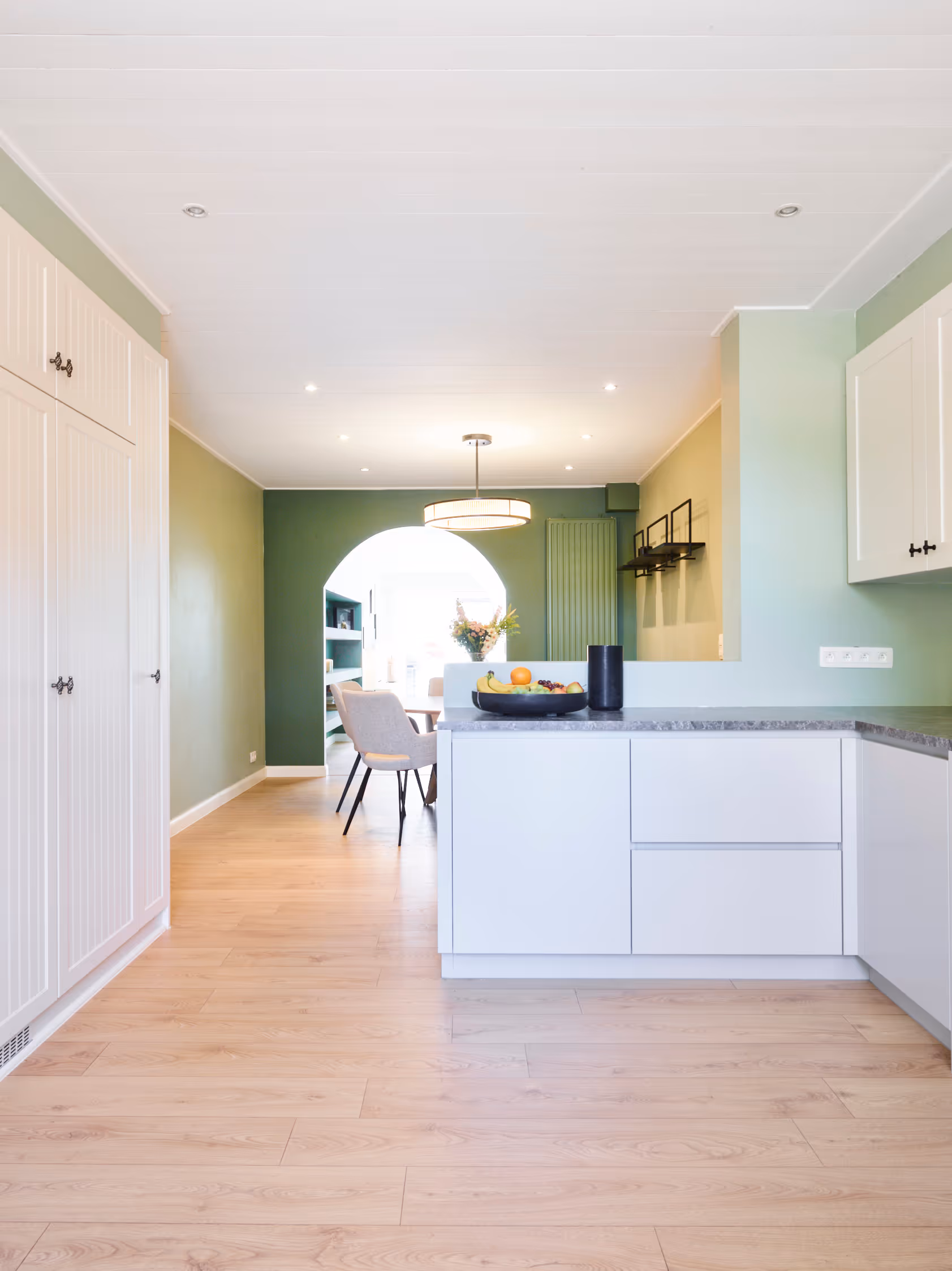 Keuken na totaalrenovatie met zicht op de eetruimte en doorgang naar leefruimte.