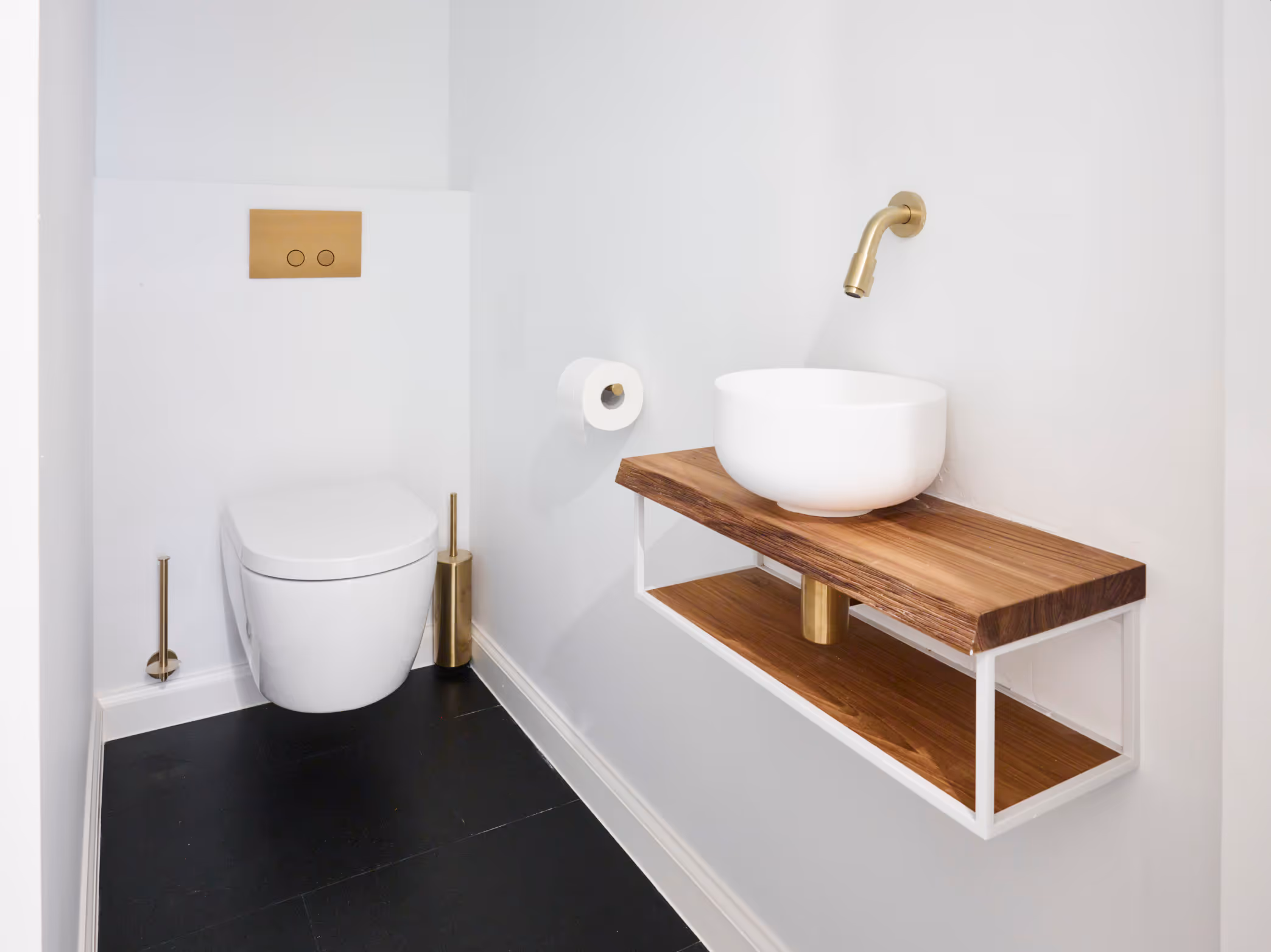 Toiletruimte na totaalrenovatie met donkere vloertegels en houten meubel.