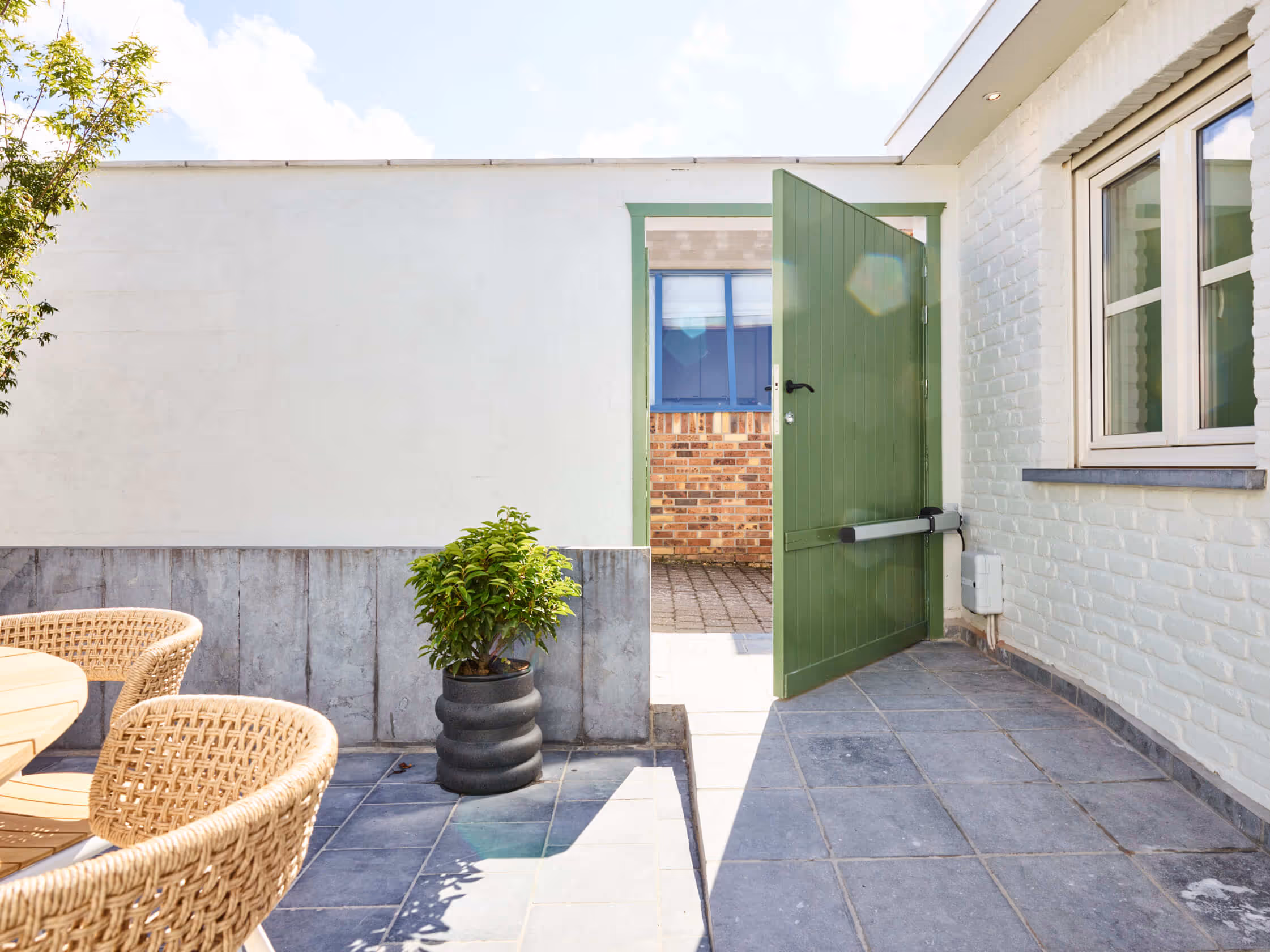 Toegangsdeur naar binnenkoer met automatische functie voor rolstoelgebruikers.