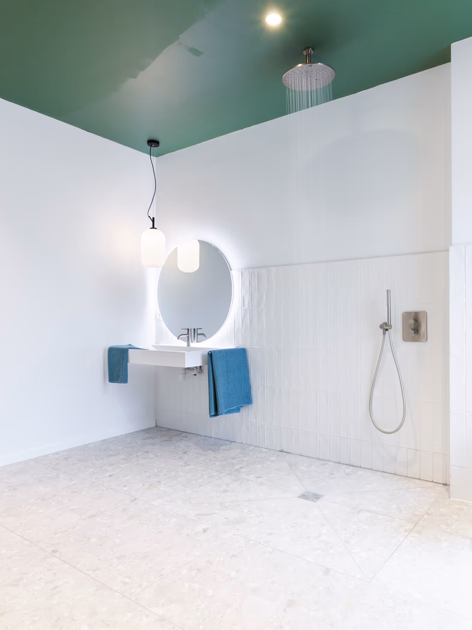 Rolstoeltoegankelijke badkamer na totaalrenovatie met verhoogde wastafel en open douche.